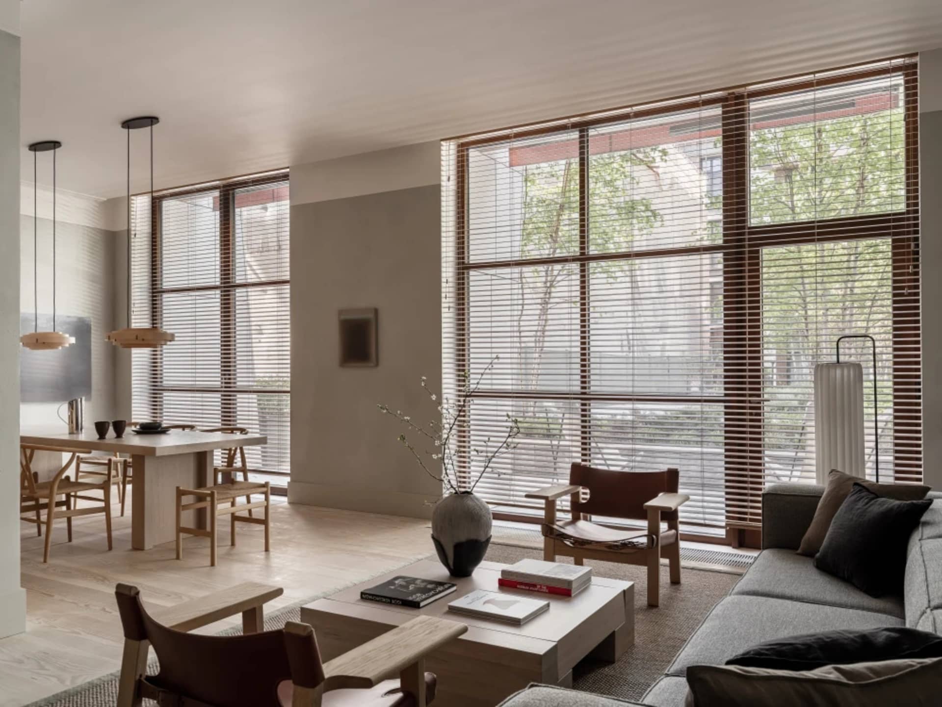 A modern minimalist living room featuring natural wood furniture and fabric upholstery, with a large window and a simple coff