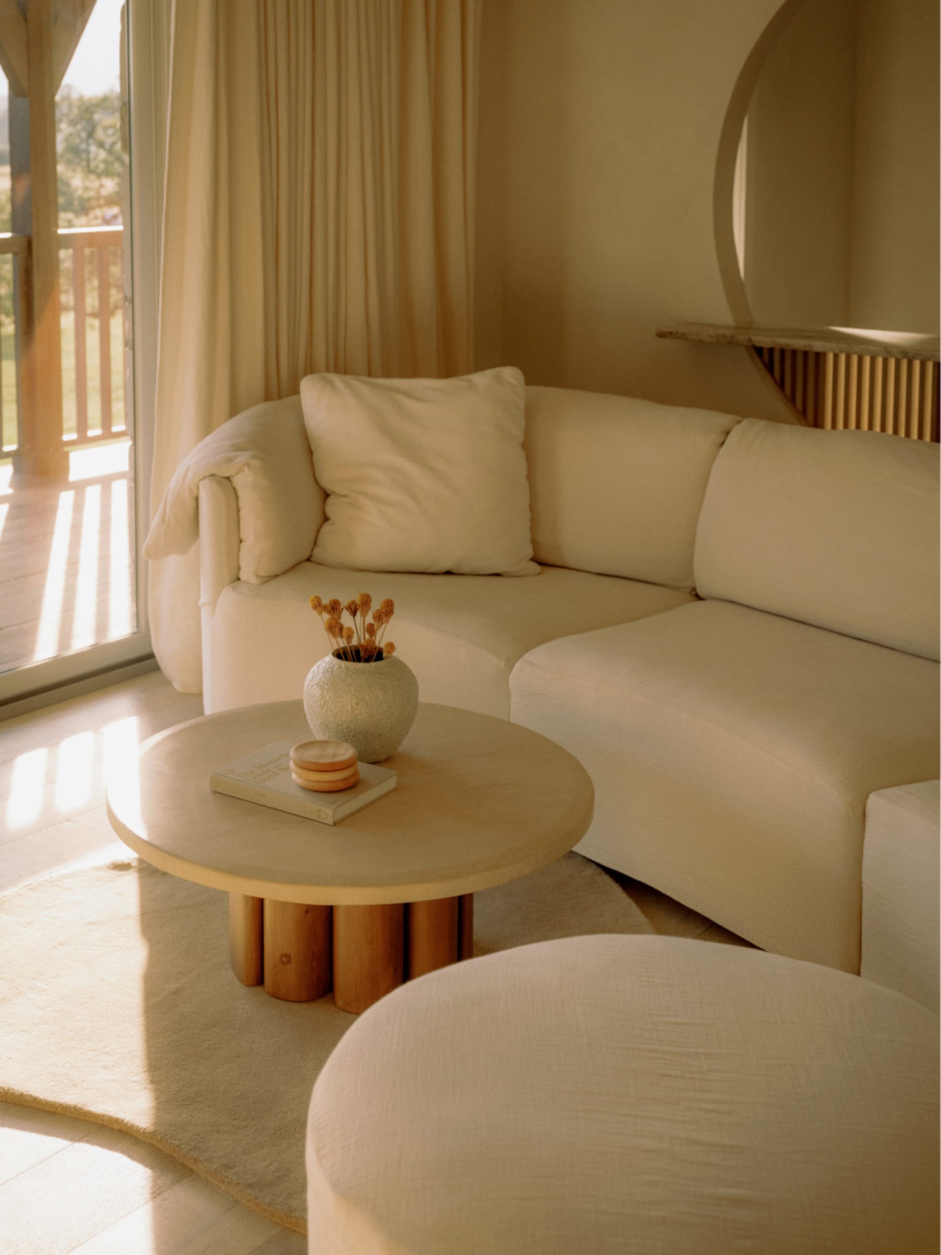 A modern, white fabric sofa in a contemporary living room setting with a round table and natural light.