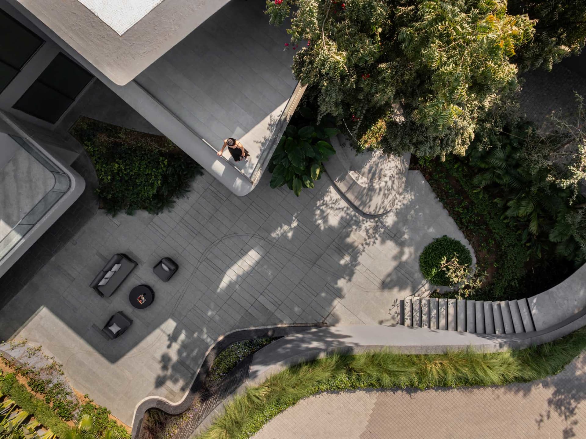 A modern urban plaza with concrete pathways and lush greenery.