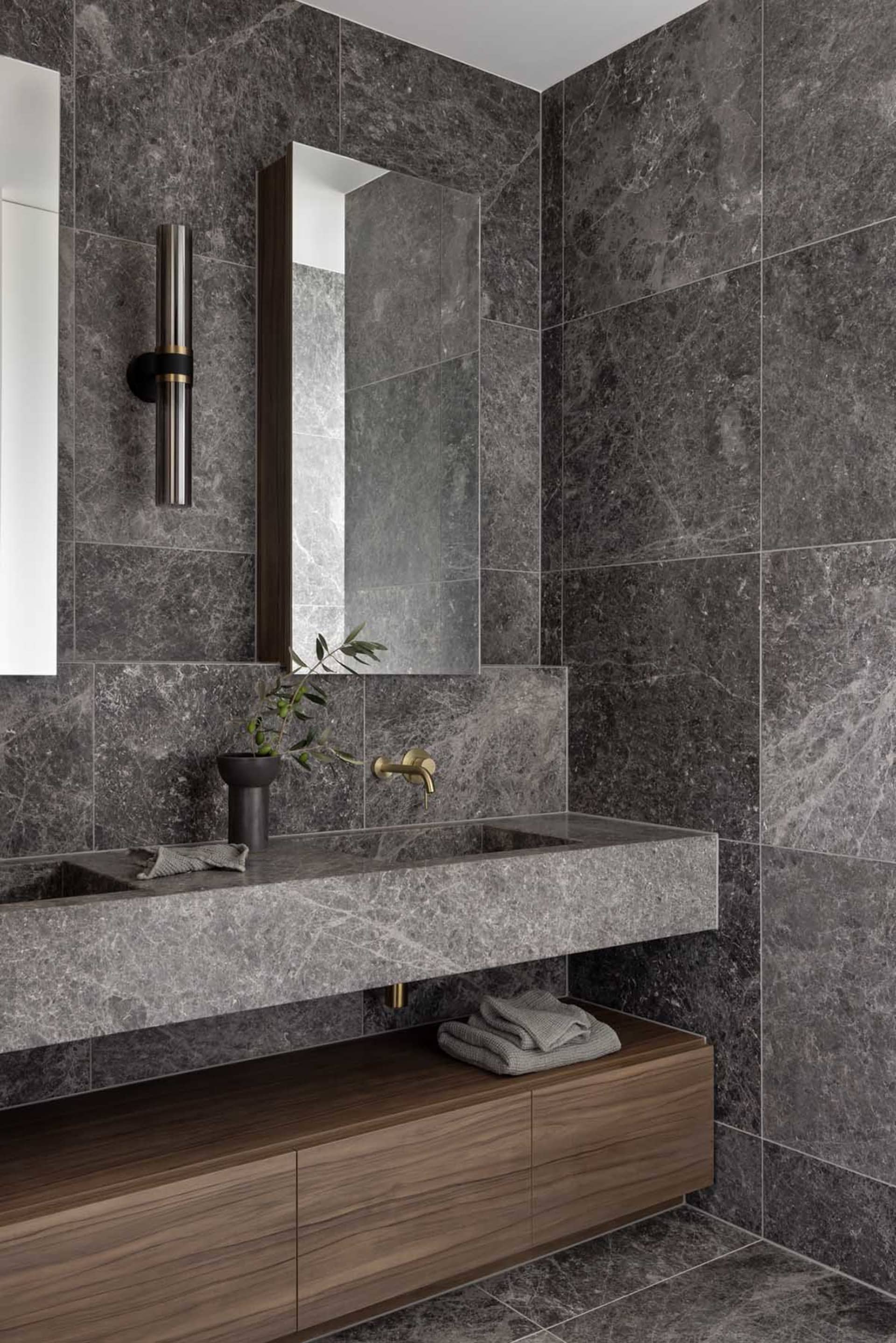 Modern bathroom with a marble sink, wooden vanity, and a tall rectangular mirror.