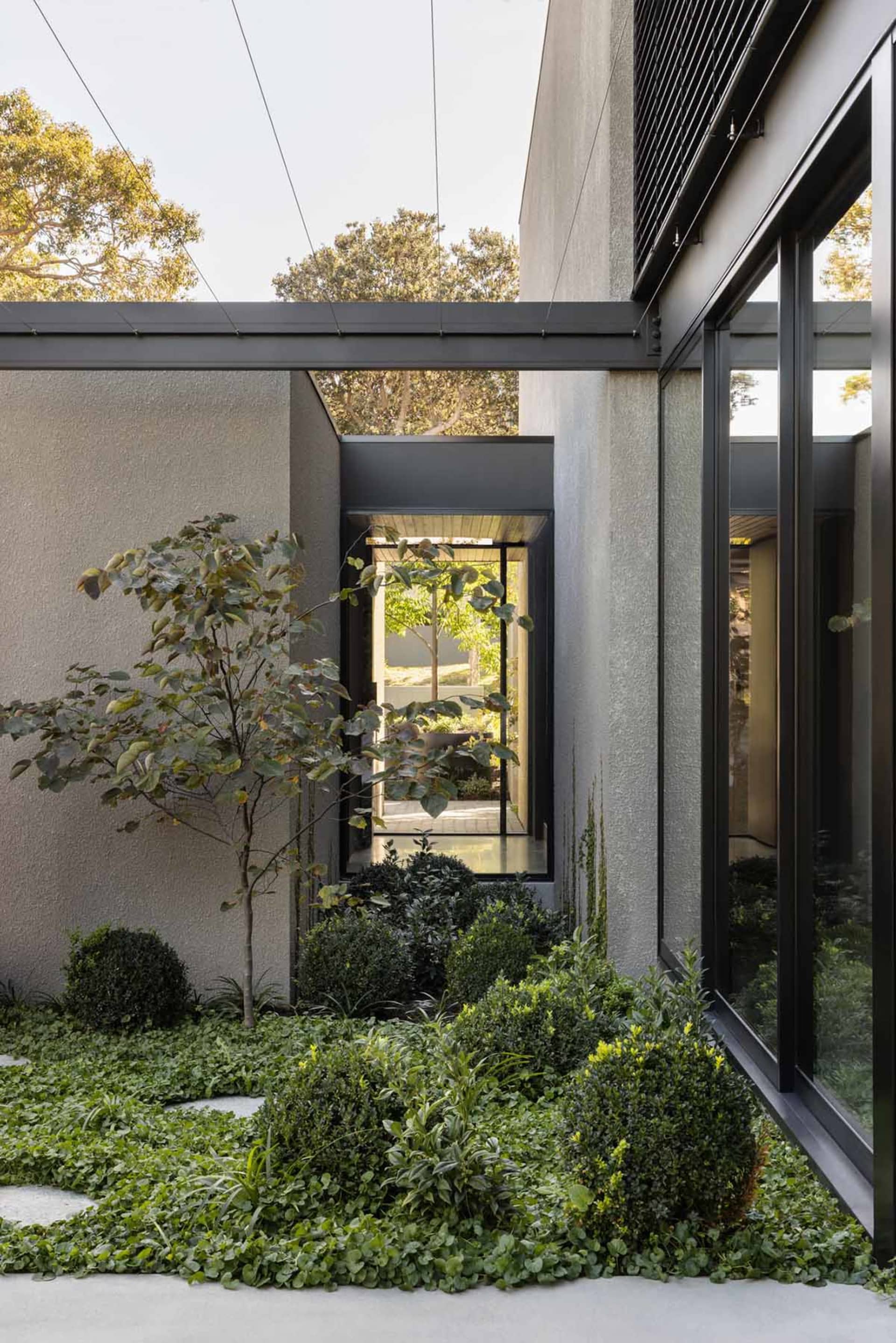 Modern residential exterior featuring concrete walls and large windows.