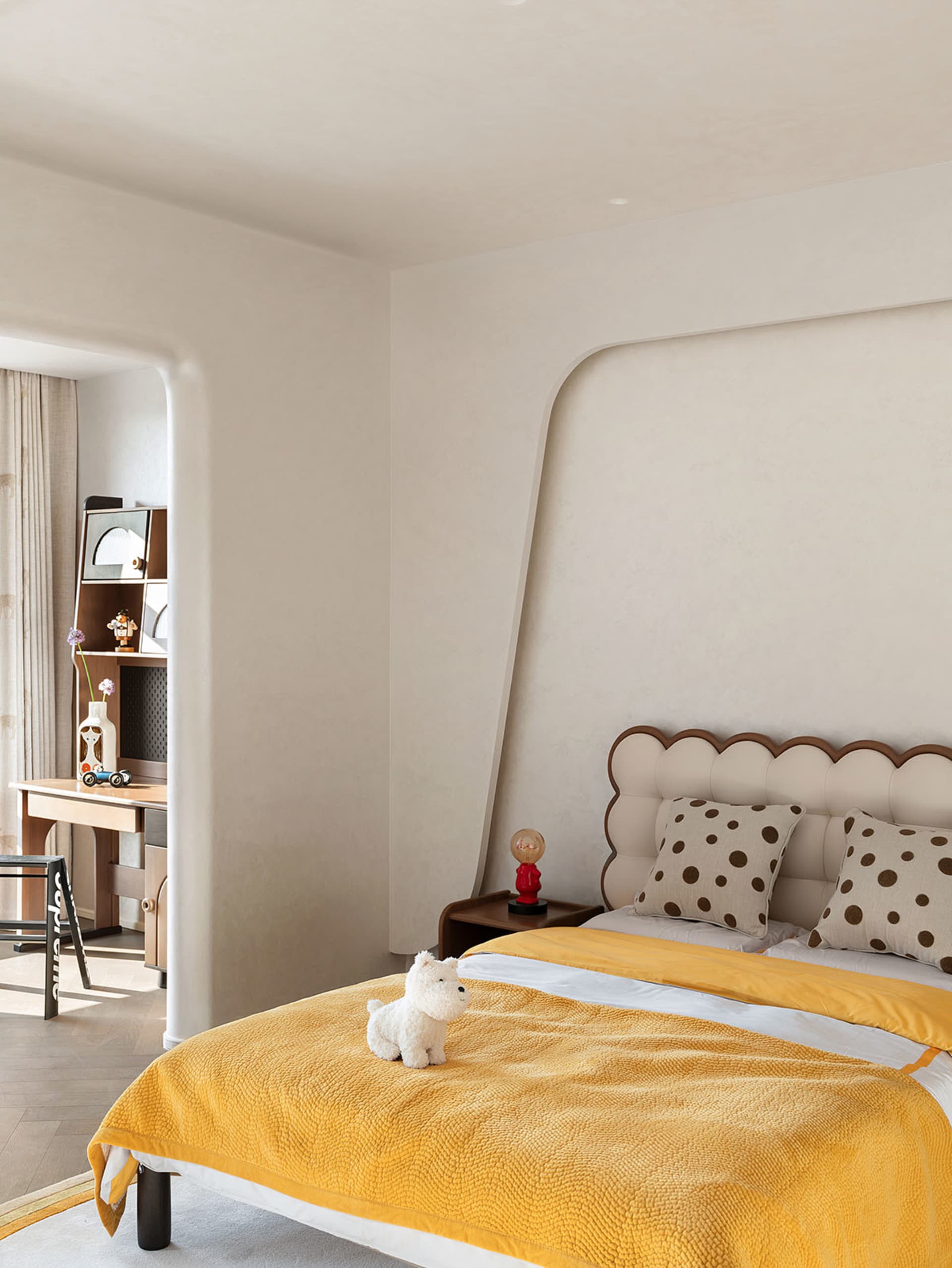 A minimalist bedroom featuring a yellow bedspread and dotted pillow, with a small table nightstand beside the bed.