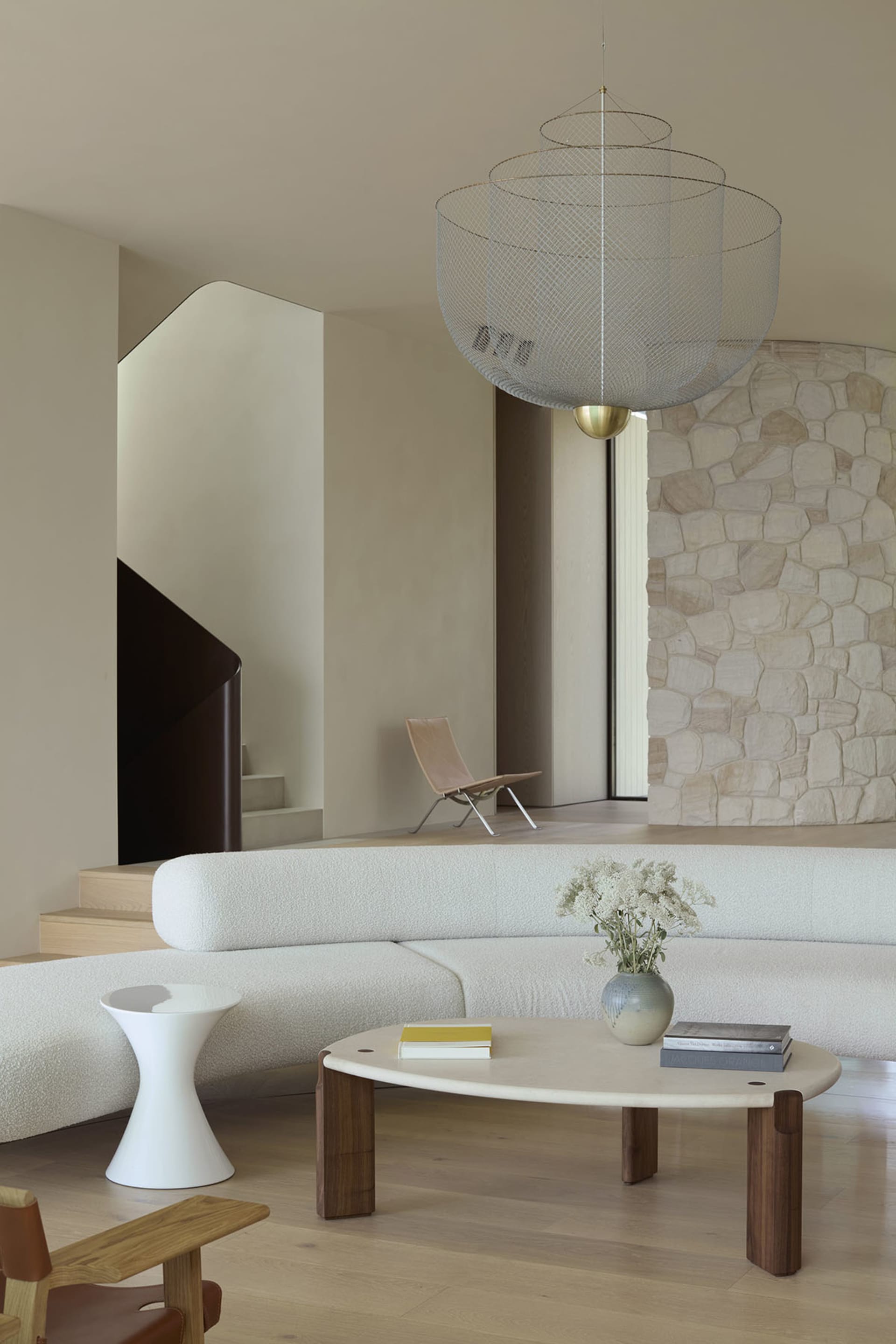 Modern living room featuring a curved sofa, coffee table, and wire chandelier hanging from the ceiling.
