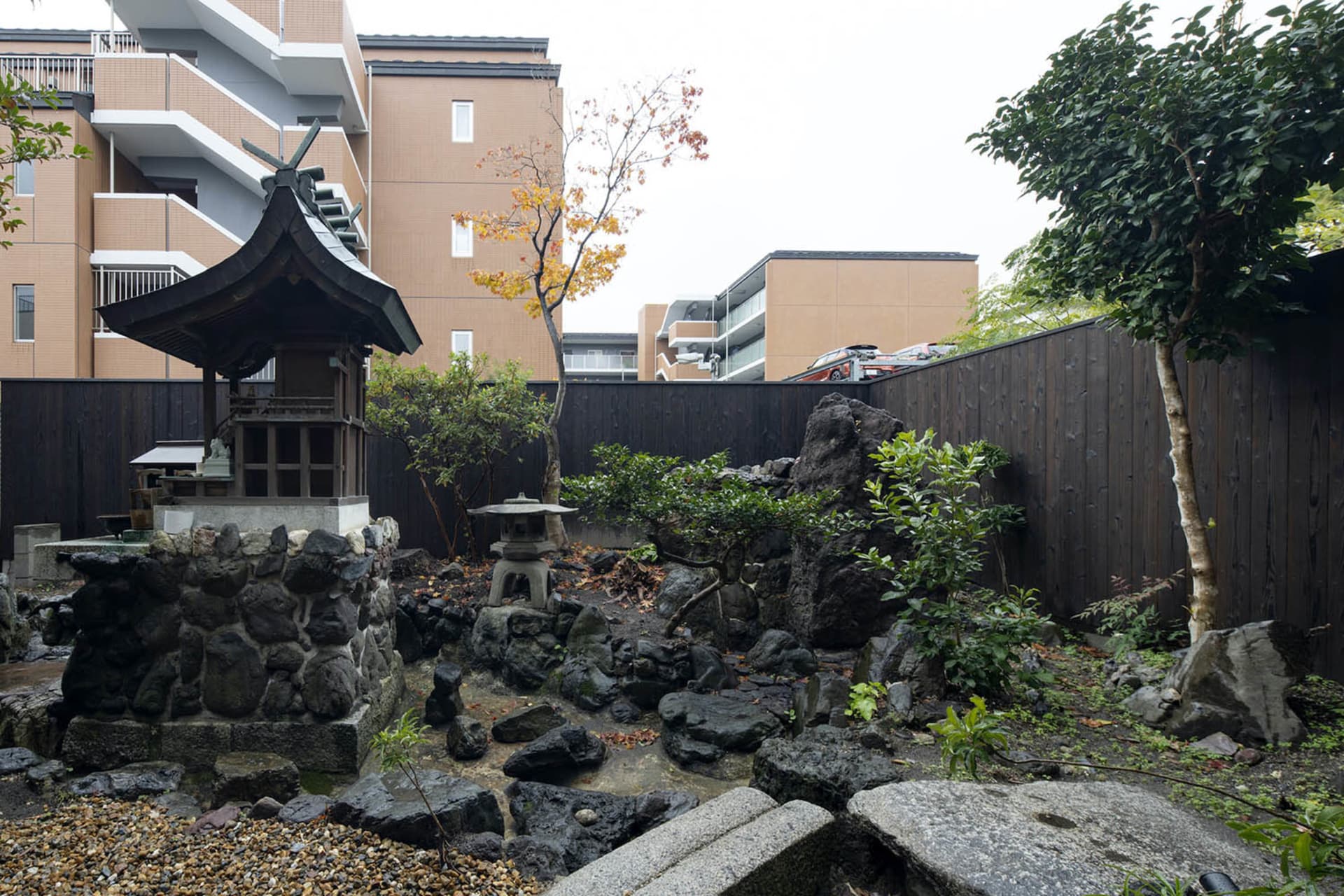 A serene Japanese garden featuring a stone monument, rock formations, and greenery.