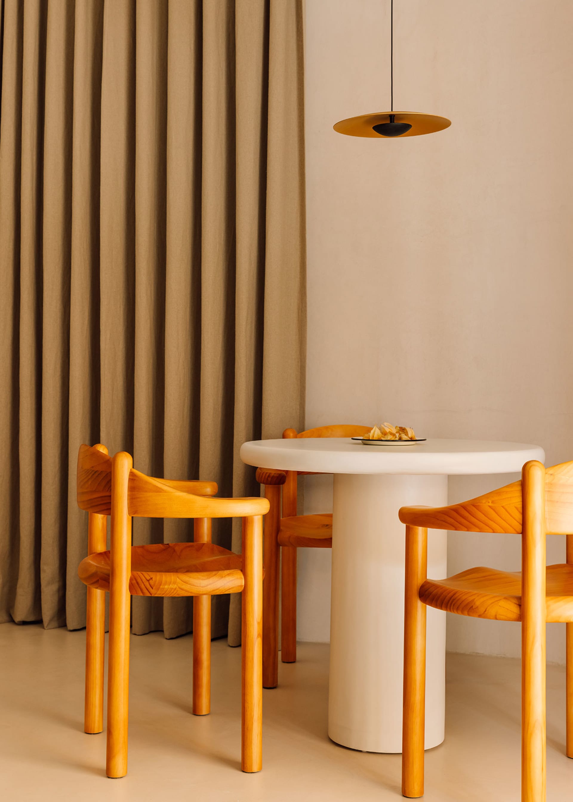 A minimalist dining room featuring wooden furniture and a white table.