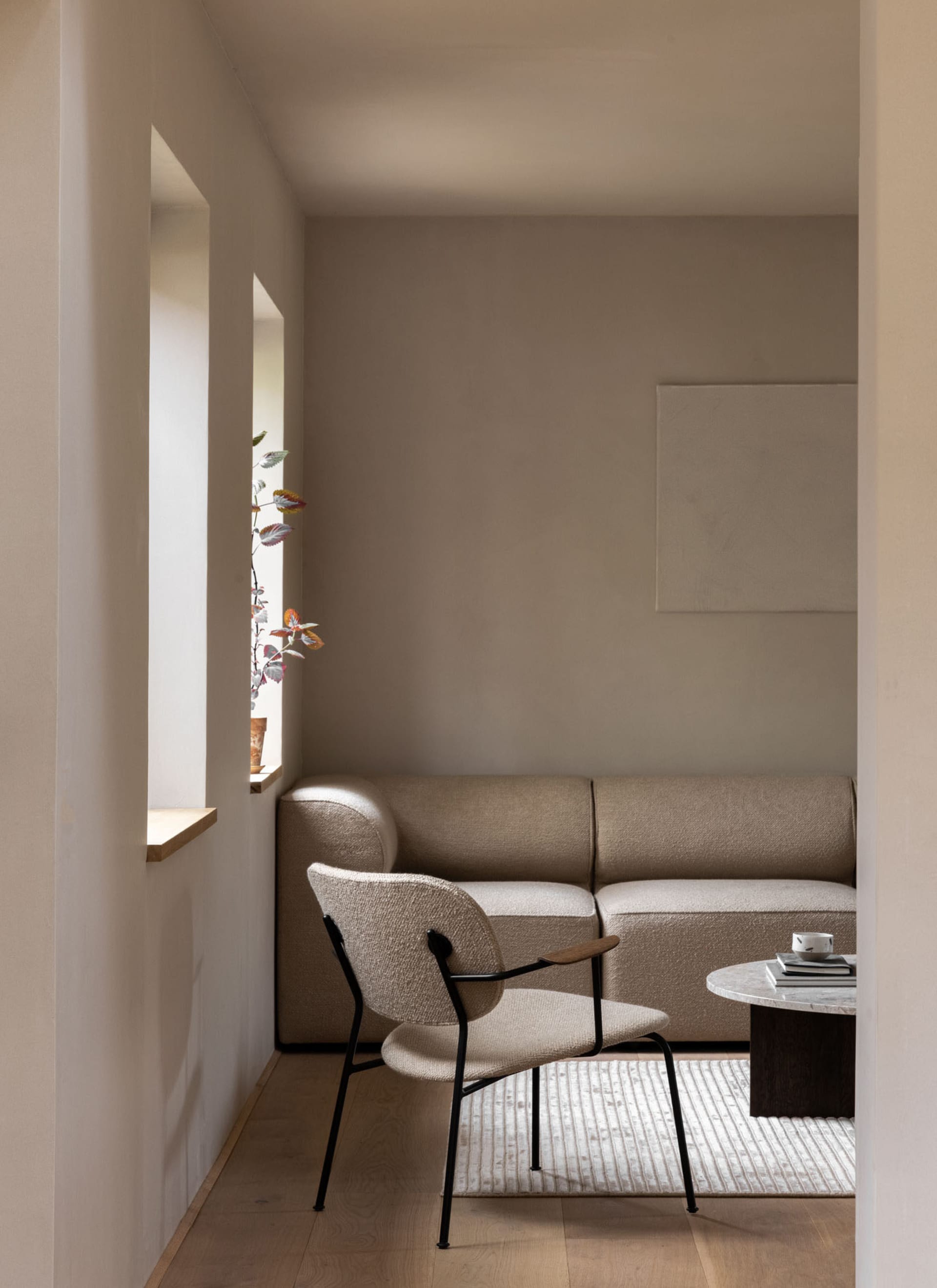 Modern minimalist living room with beige furniture and a round coffee table.