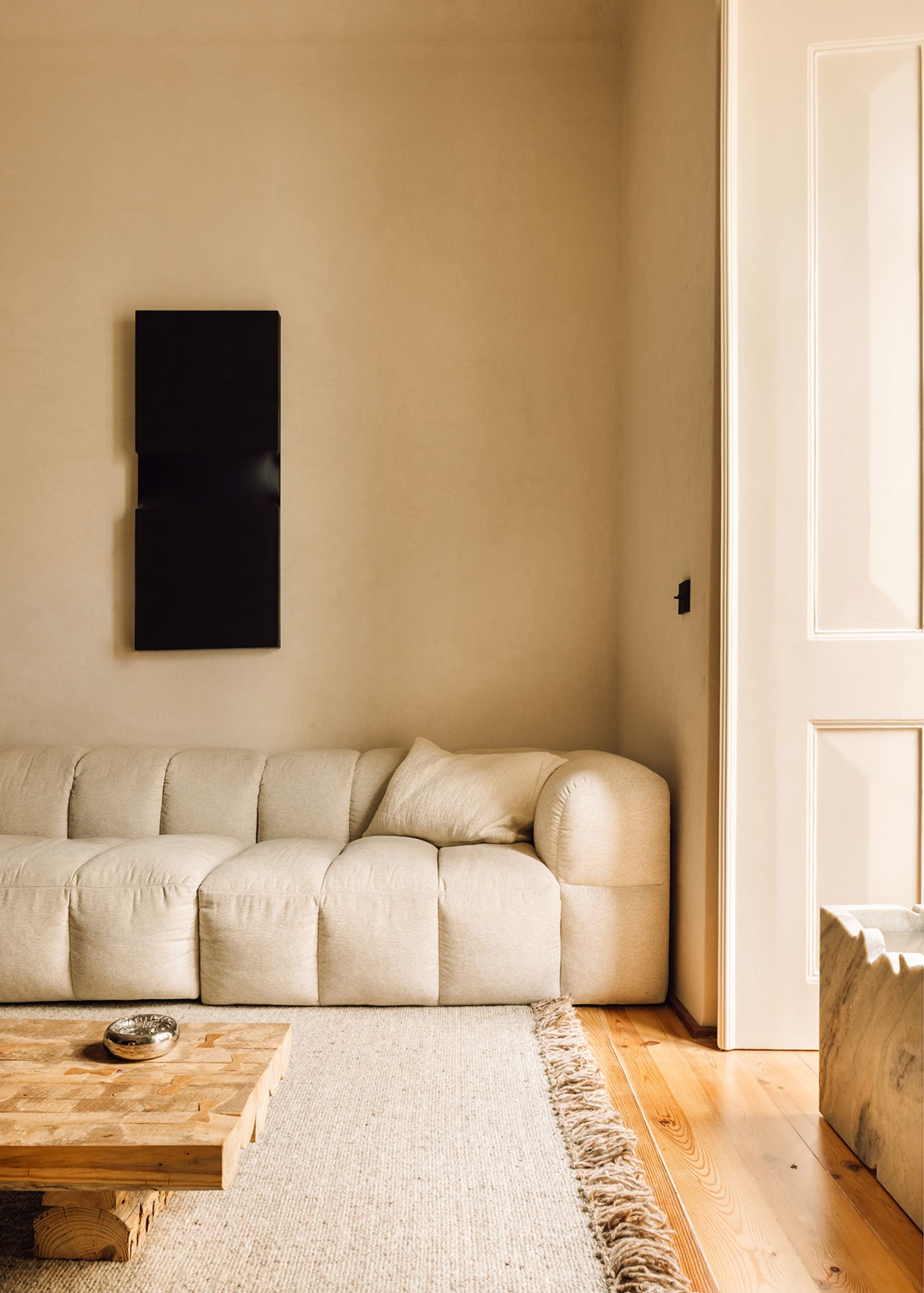 A minimalist living room featuring a white sofa with a textured pattern and a wooden coffee table.