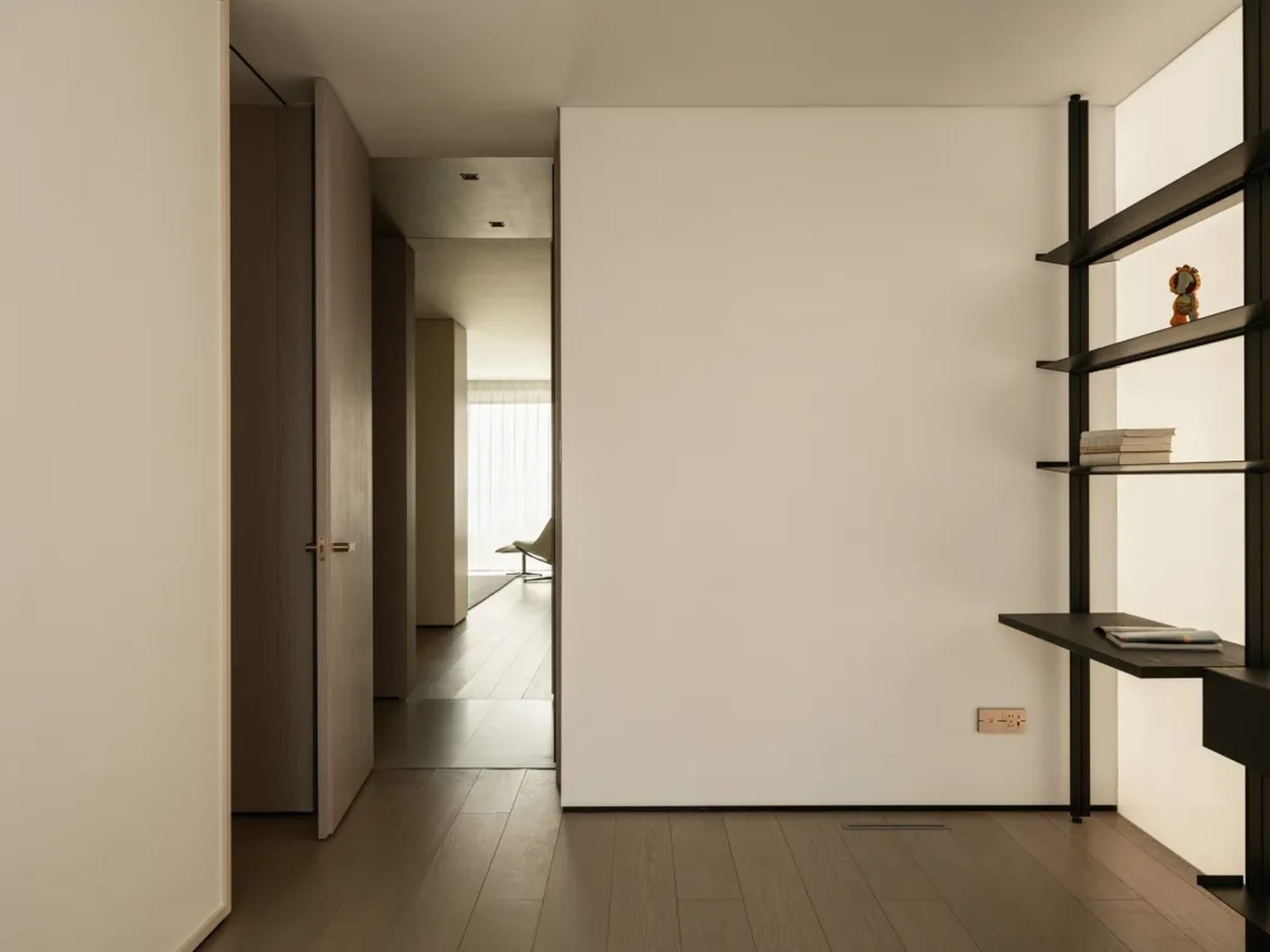 Spacious, minimalist-style living room with a wooden floor and white walls.