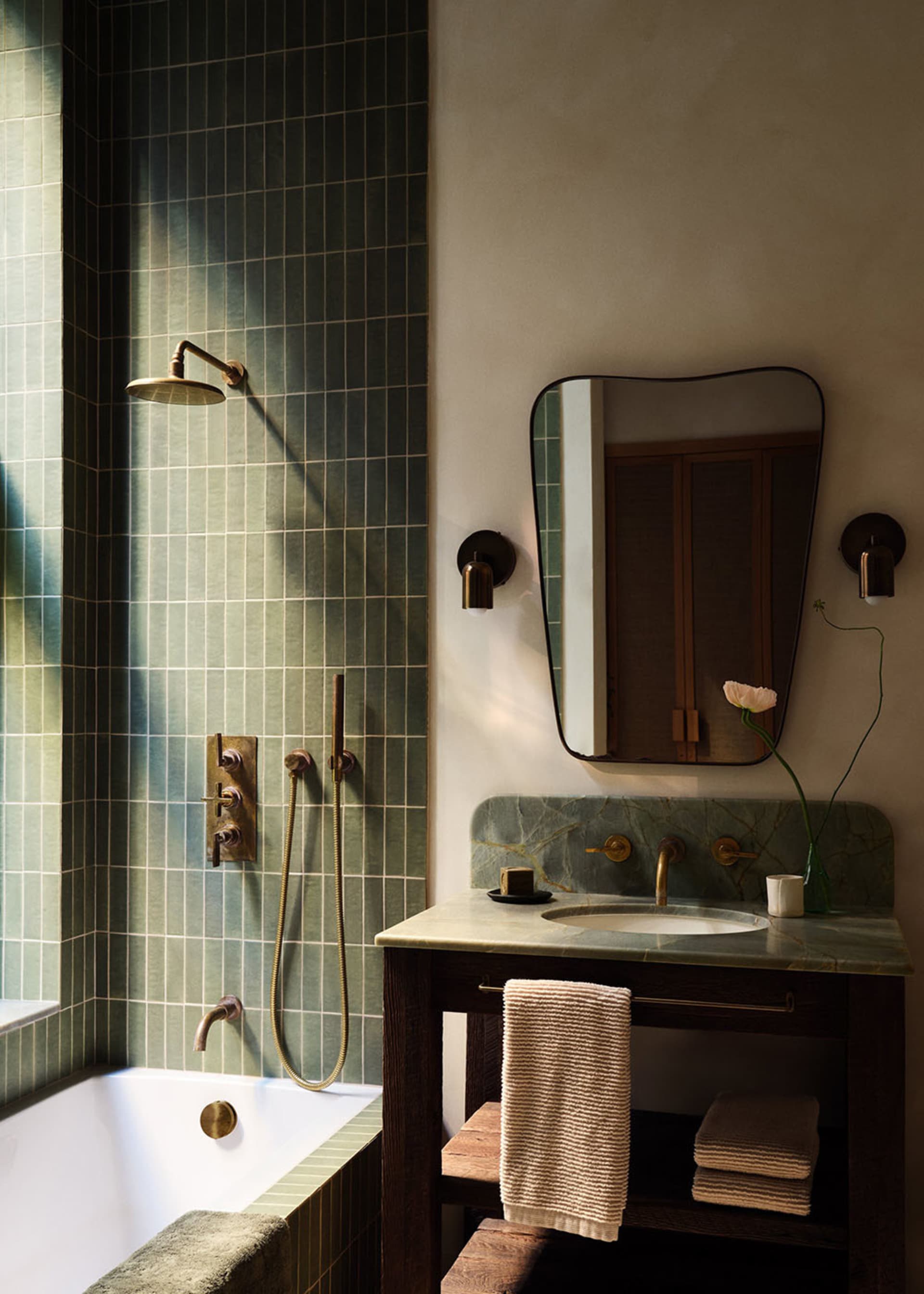 Modern minimalist bathroom with green-tiled walls and white fixtures, featuring a sink with a green marble countertop and a s