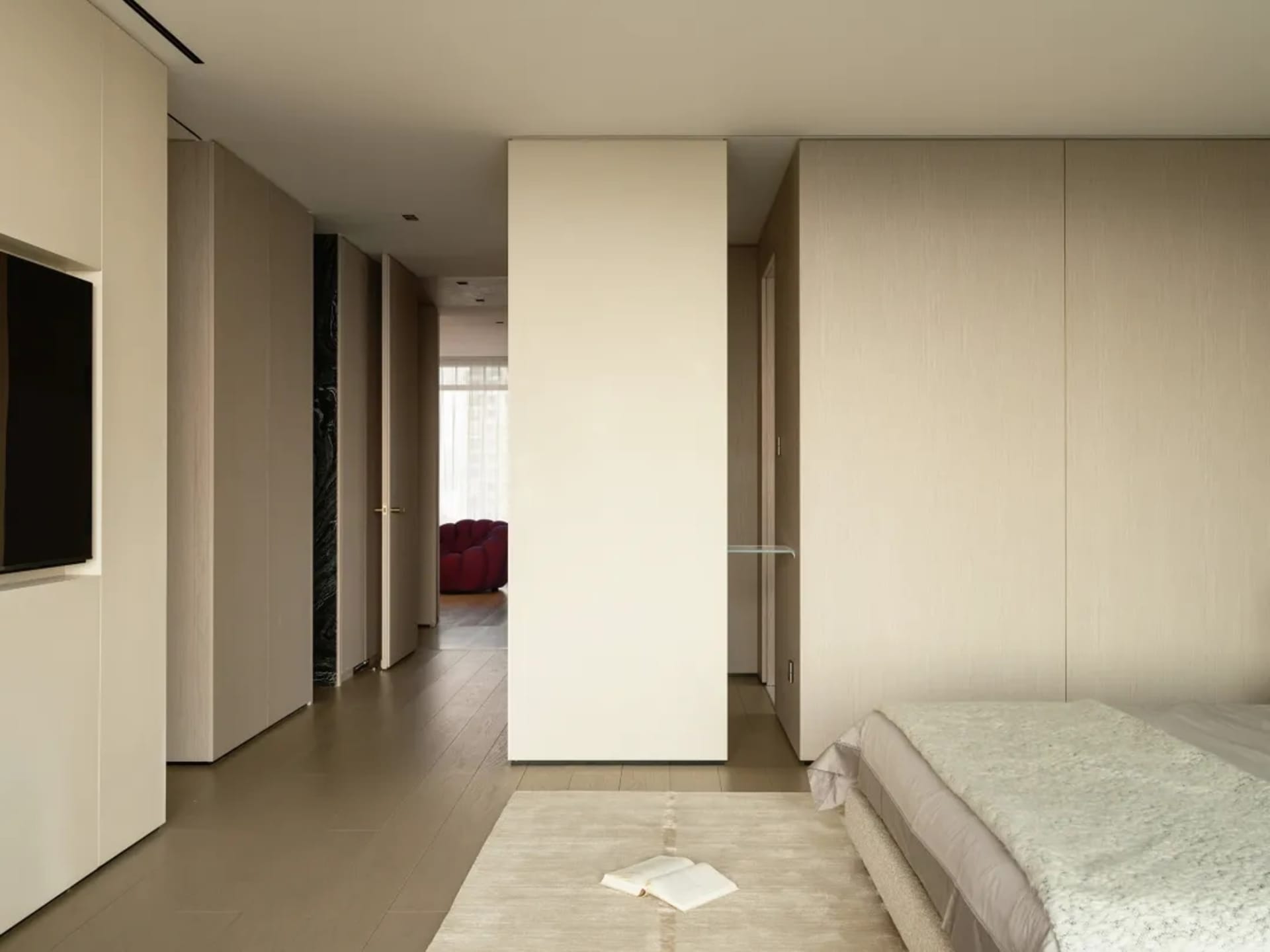 Modern bedroom with textured beige walls and wood floor, featuring a bed with beige and white bedding.