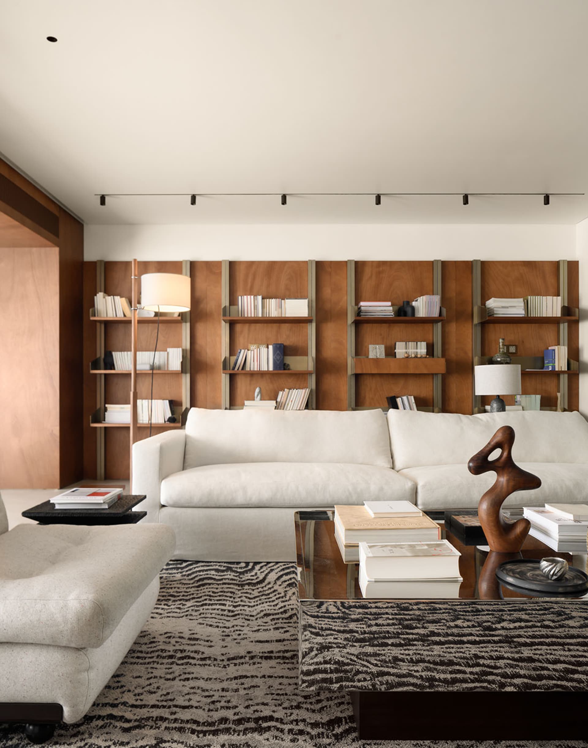 A modern living room featuring a white sofa, wooden shelves, and a floor lamp.