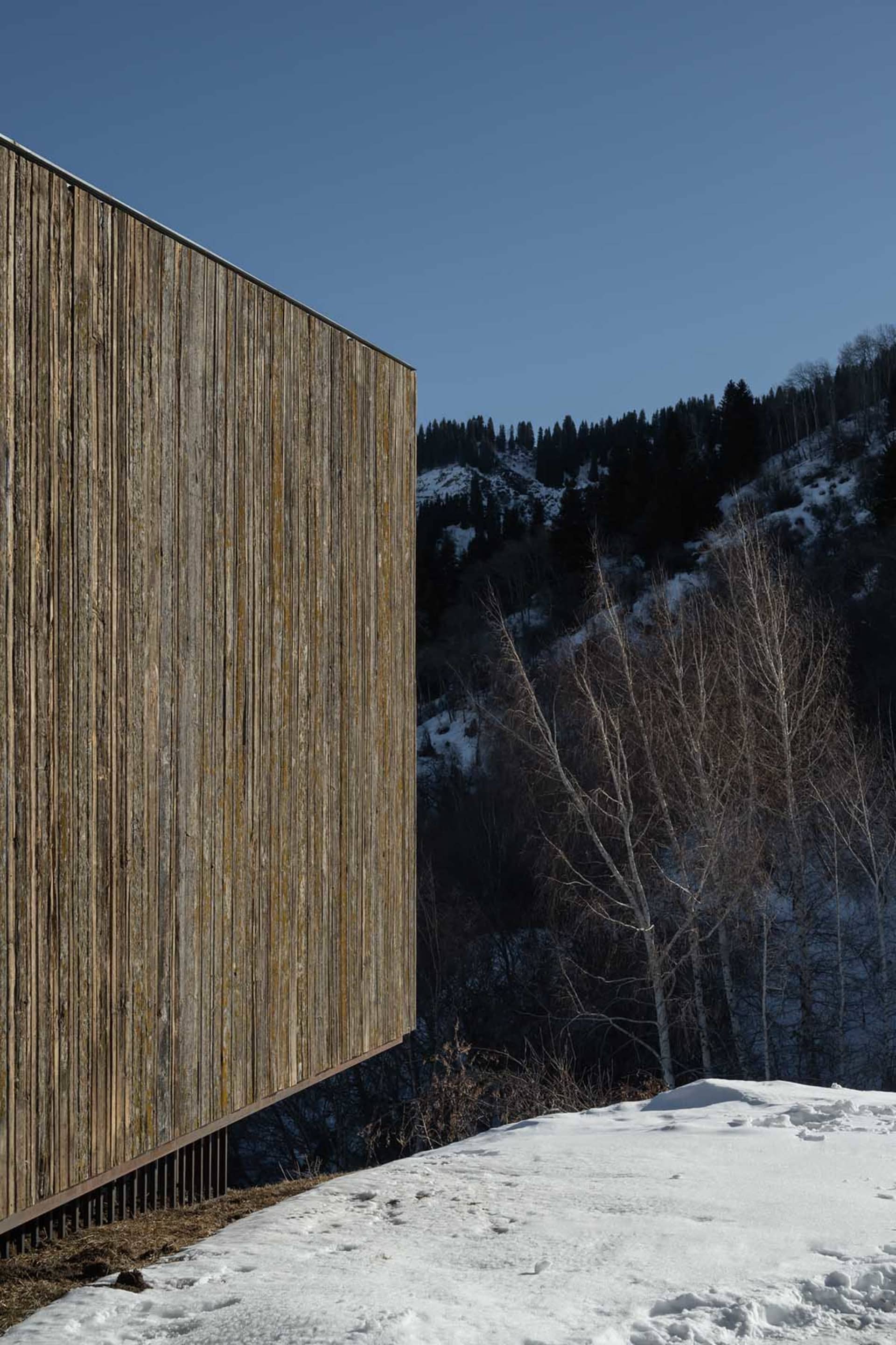 Modern minimalist building made of wood, with a clear blue sky in the background.