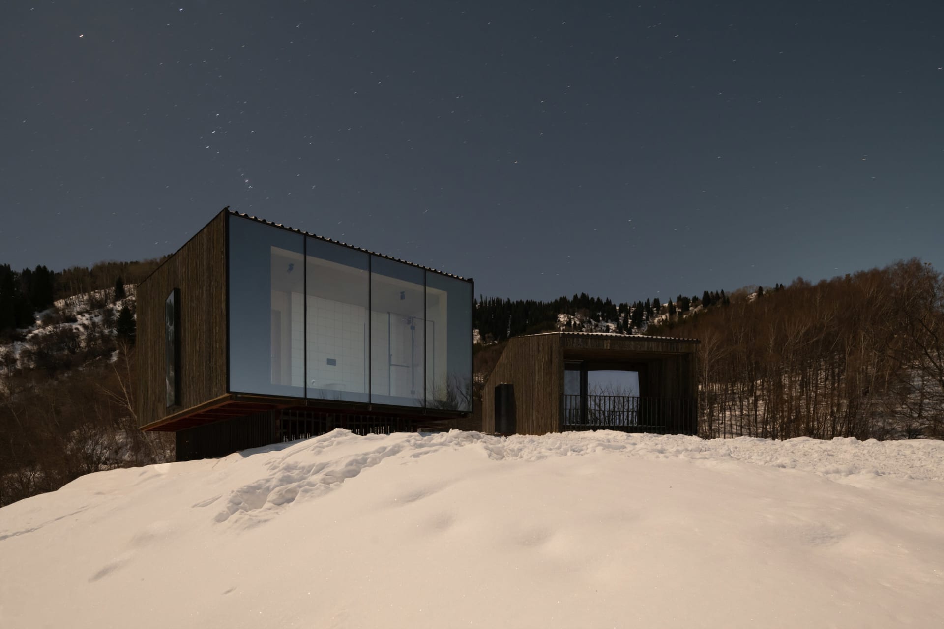 雪夜中以玻璃與木質外觀呈現的現代住宅建築。