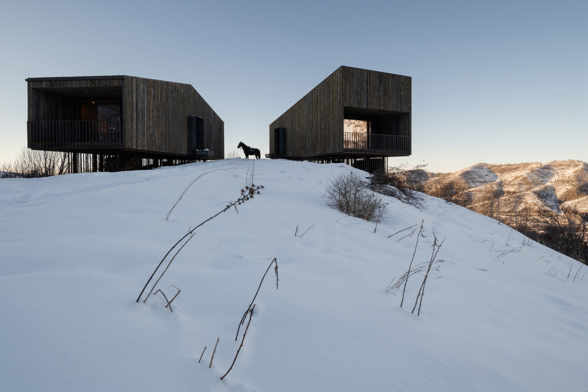 Modern houses with wood exterior on a snowy hillside.