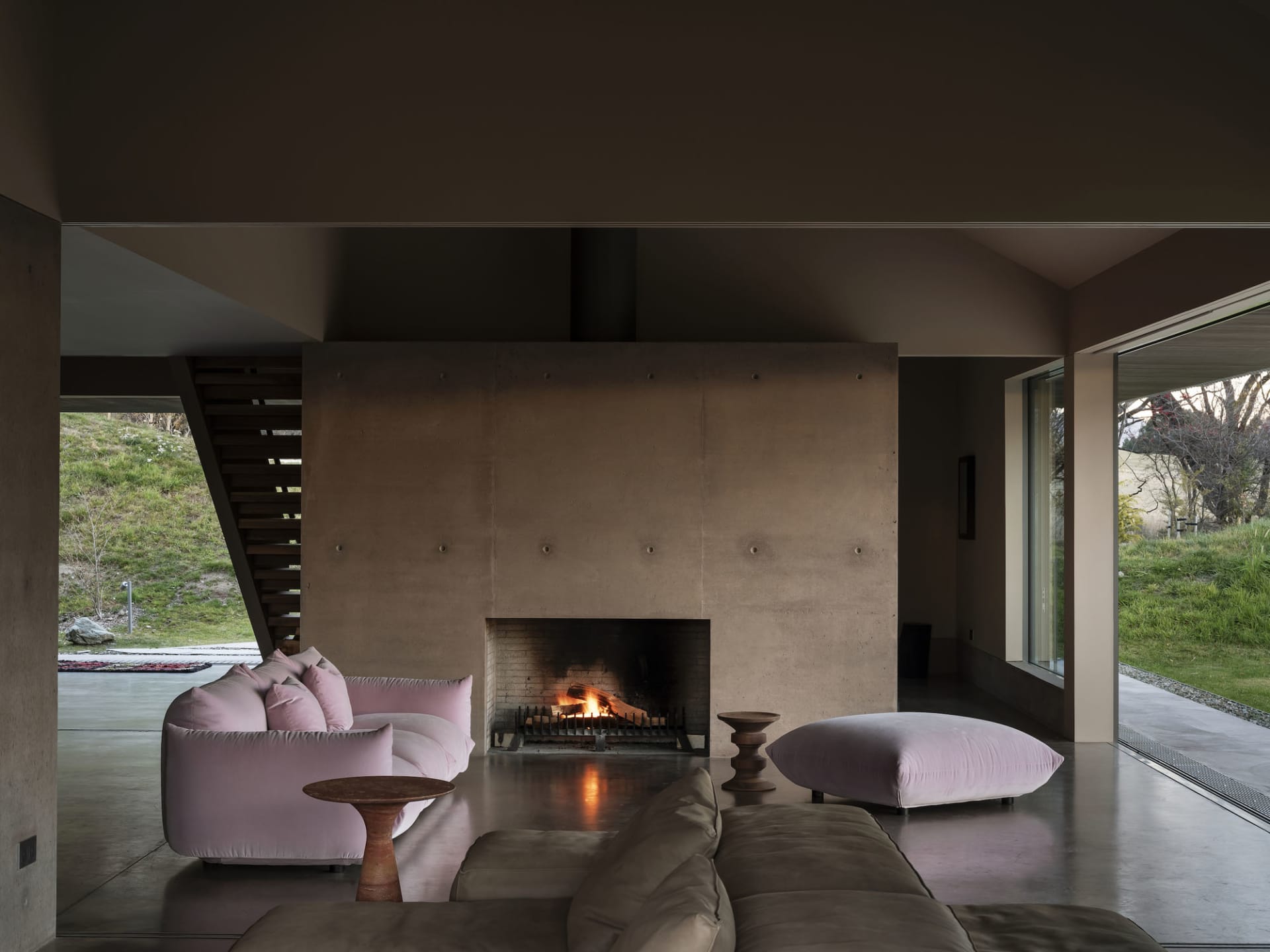 A living room with modern furniture and a large concrete fireplace.