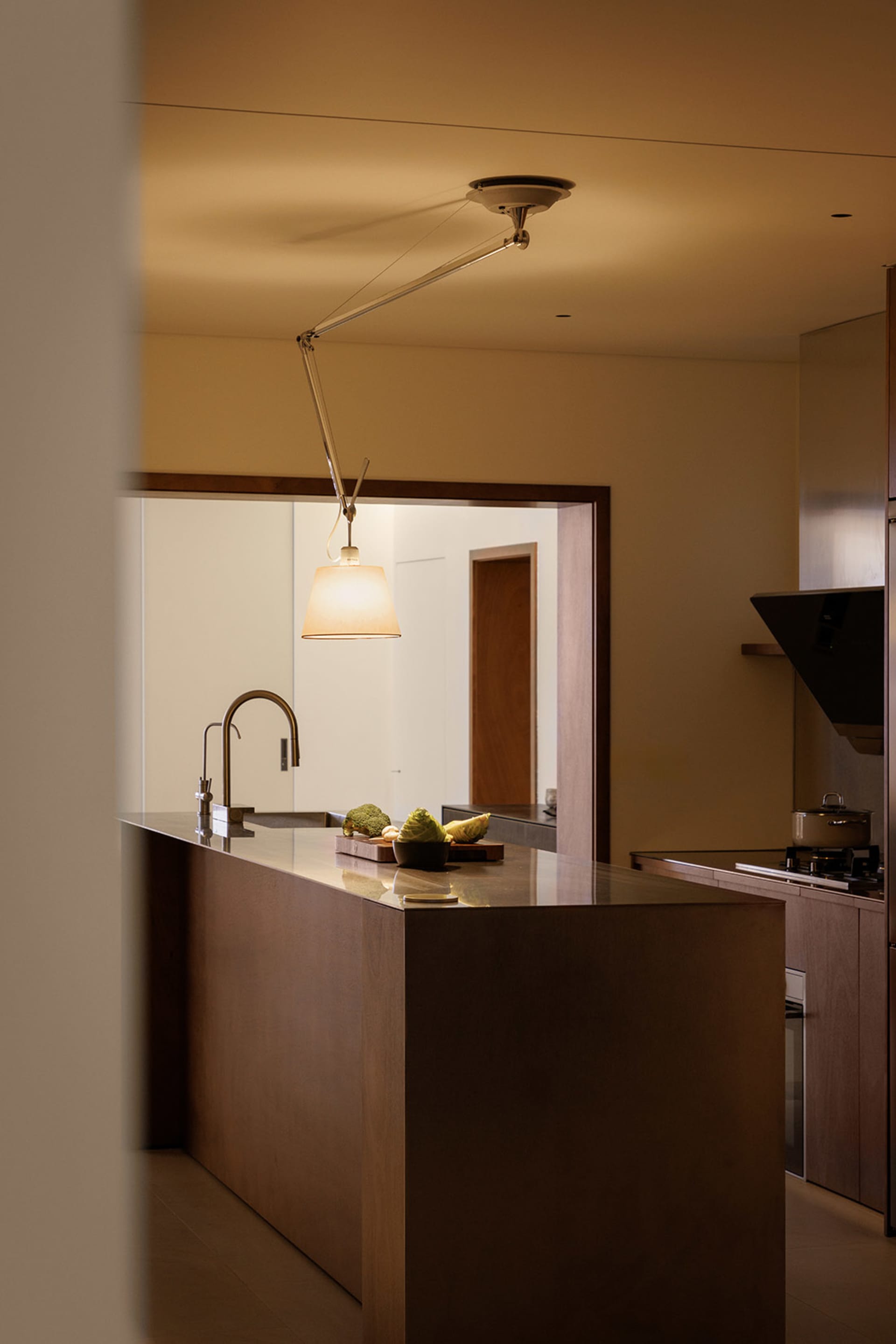 A modern, minimalist kitchen with a wooden countertop, featuring a variety of fruits on a cutting board.