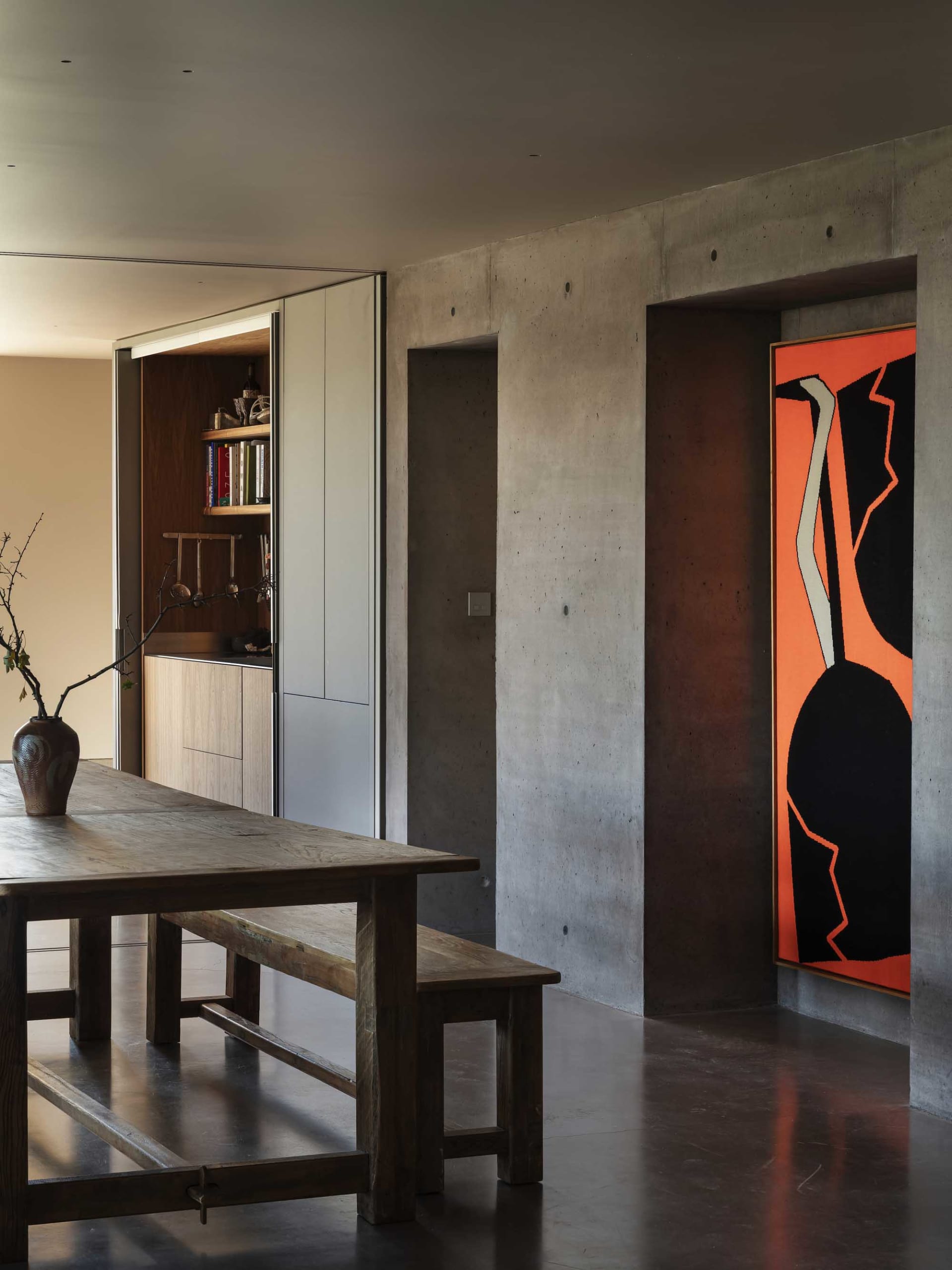 A modern minimalist interior with concrete walls and a wooden dining table.