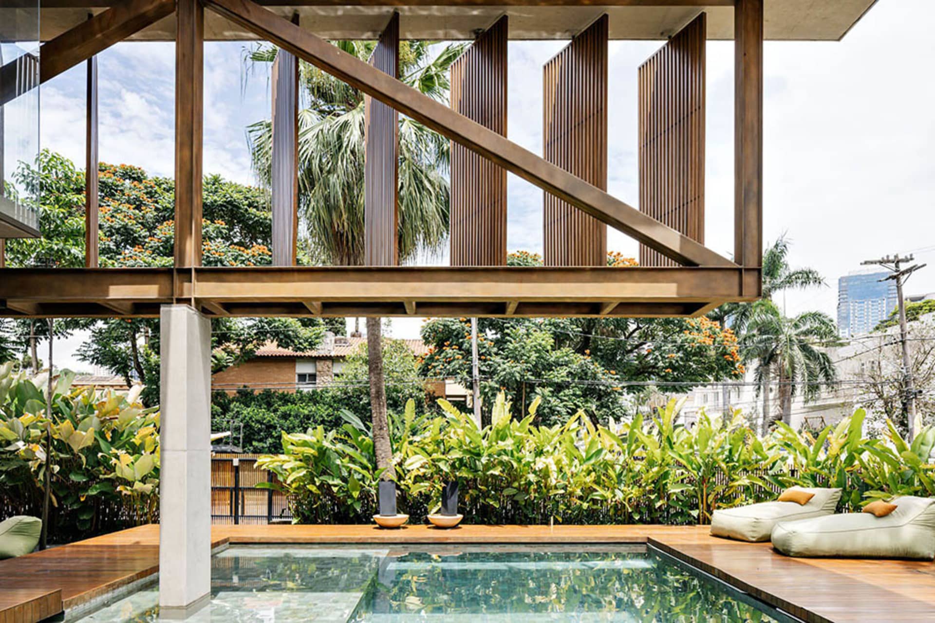 Modern residential outdoor area featuring concrete and wooden structures, surrounded by lush greenery.