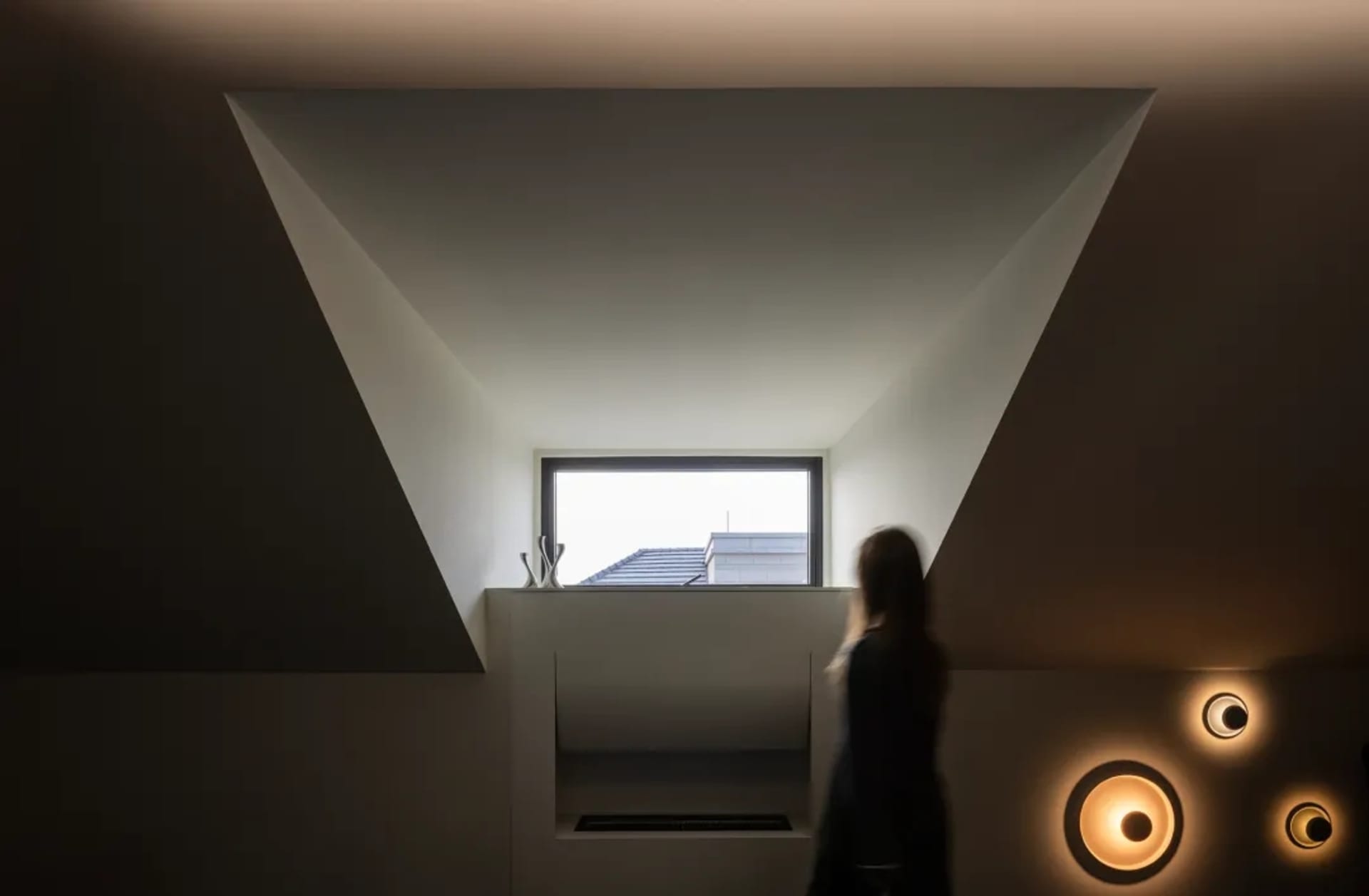 A modern interior design featuring a concrete wall with a large window and unique lighting fixtures.