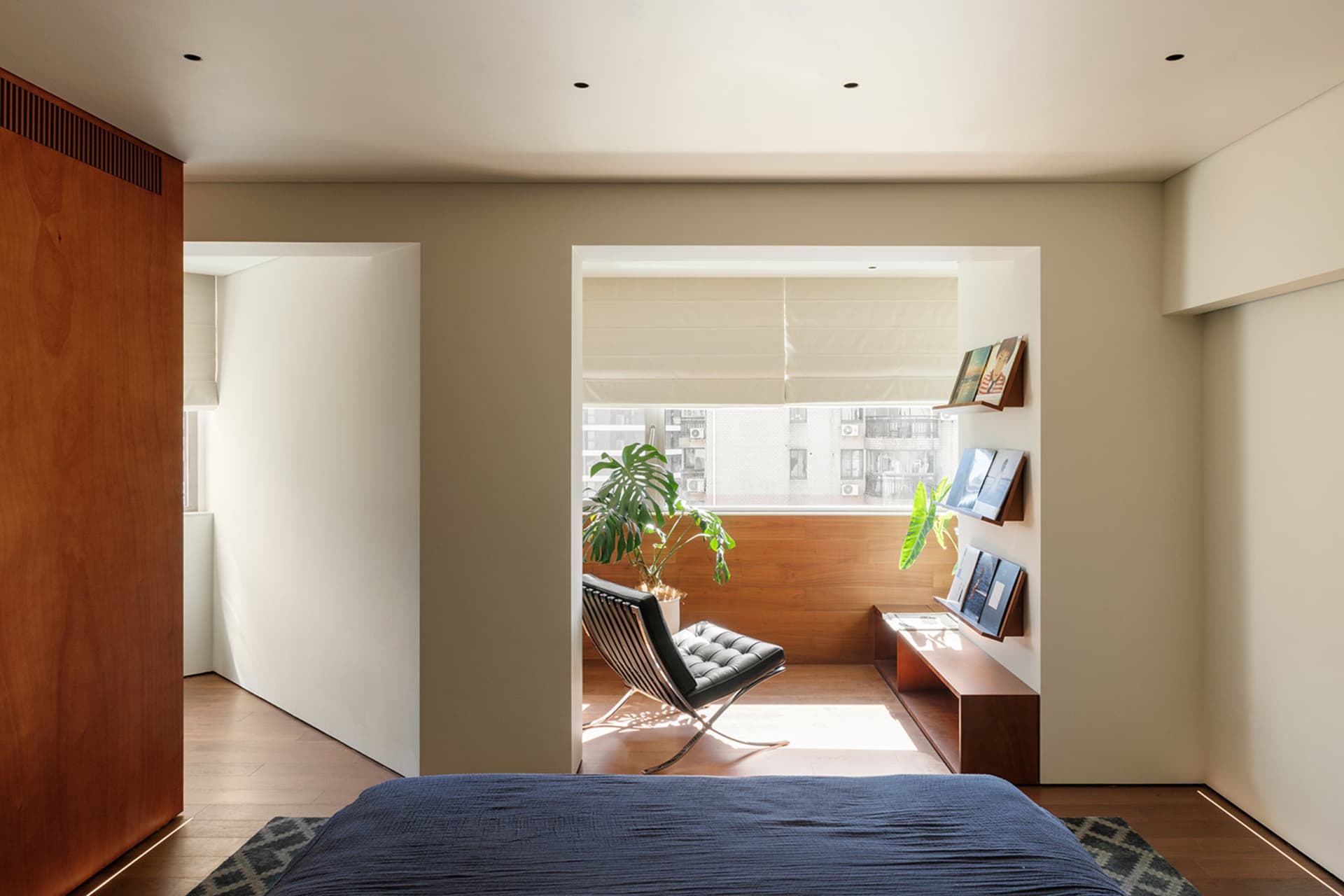 A modern minimalist bedroom with wooden walls and a grey bed.