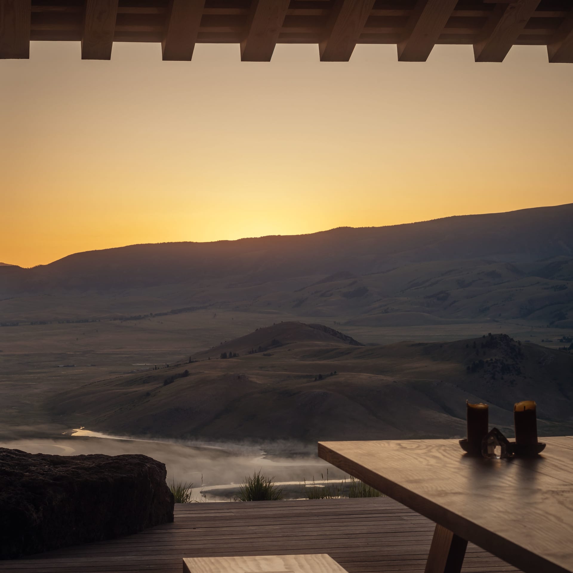 Wooden table overlooking a mountain landscape at sunset.