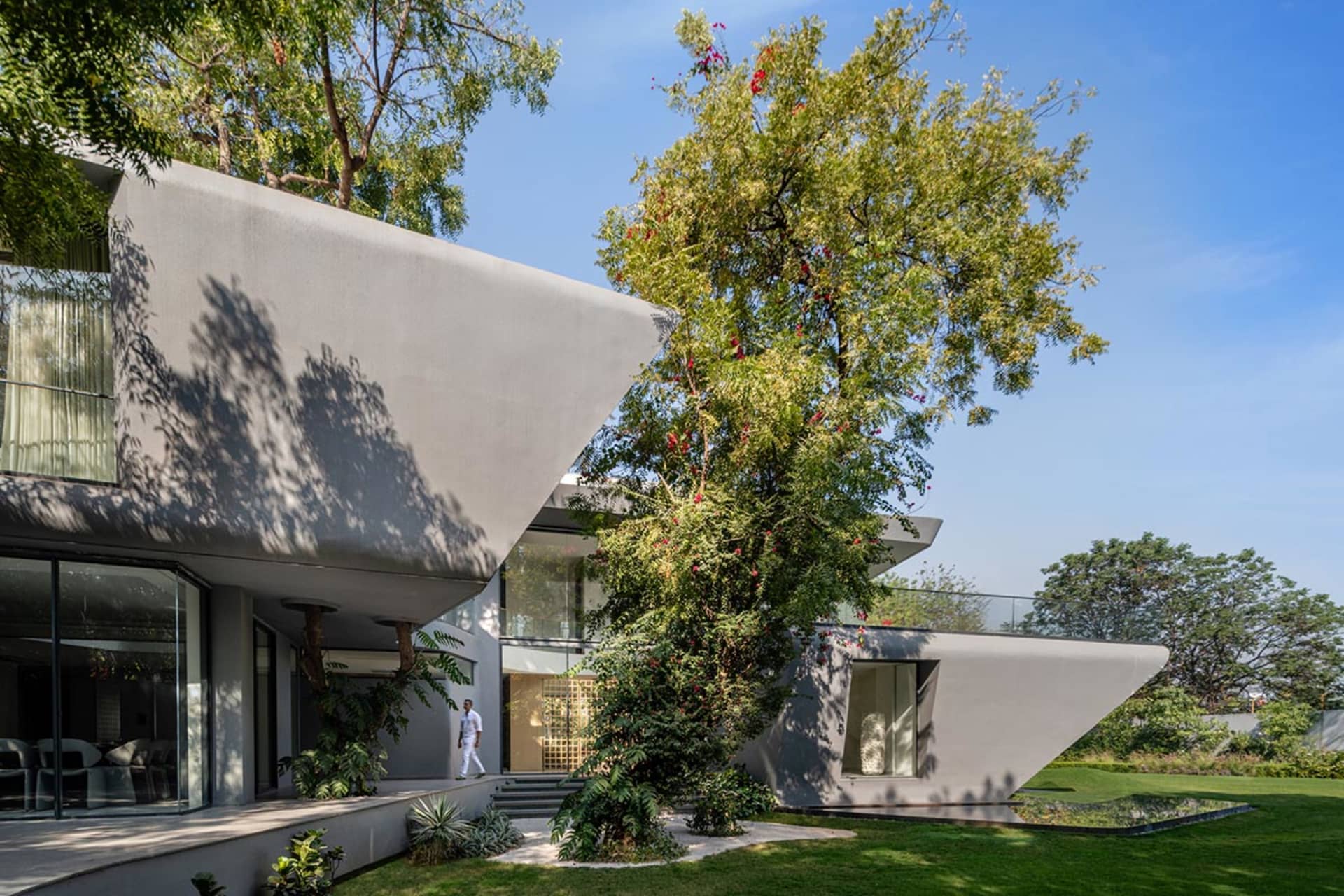 Modern house exterior with concrete walls and roof, surrounded by greenery.