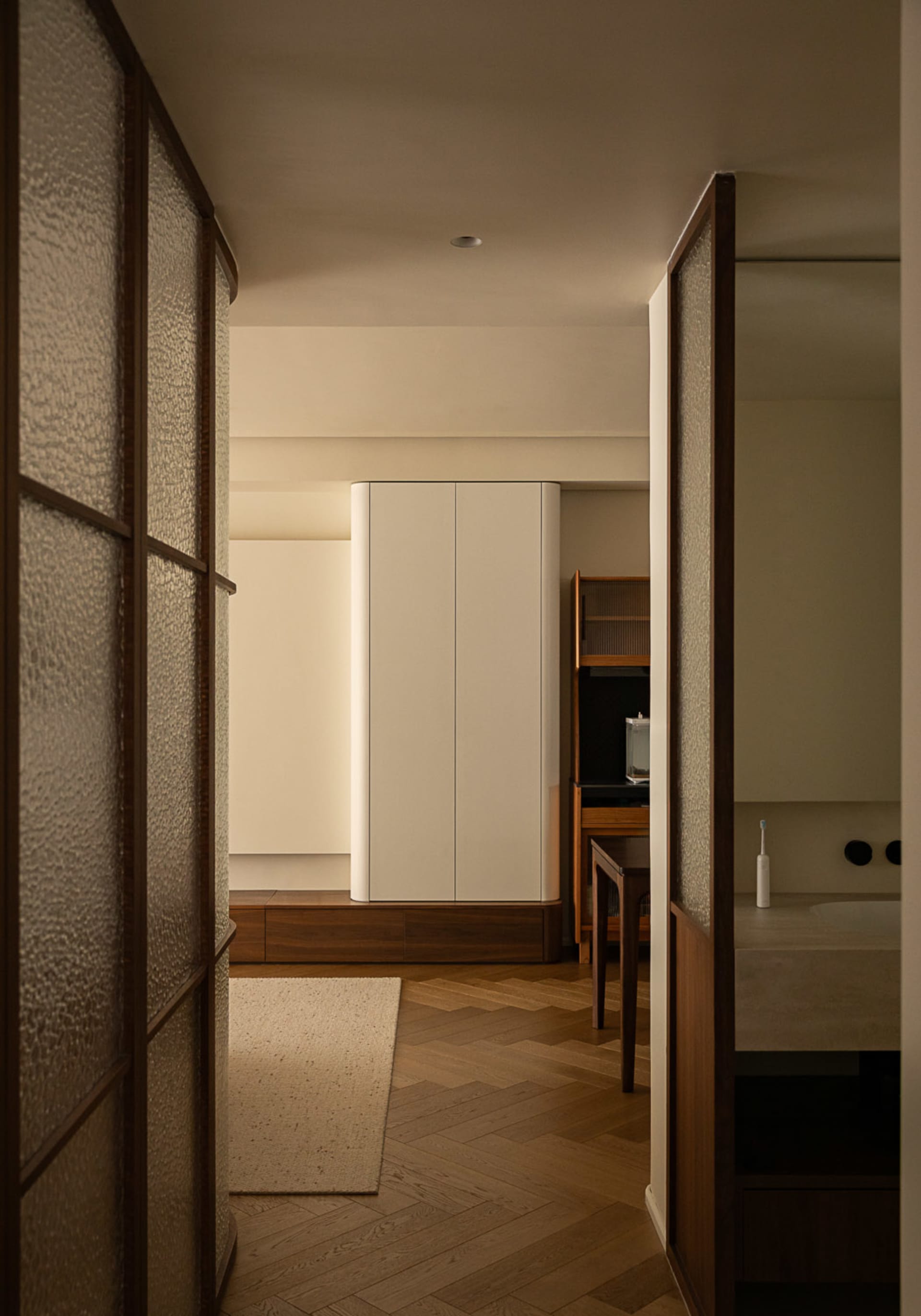 Modern minimalist bedroom featuring light-colored wooden floors, brass accents, and white cabinets.