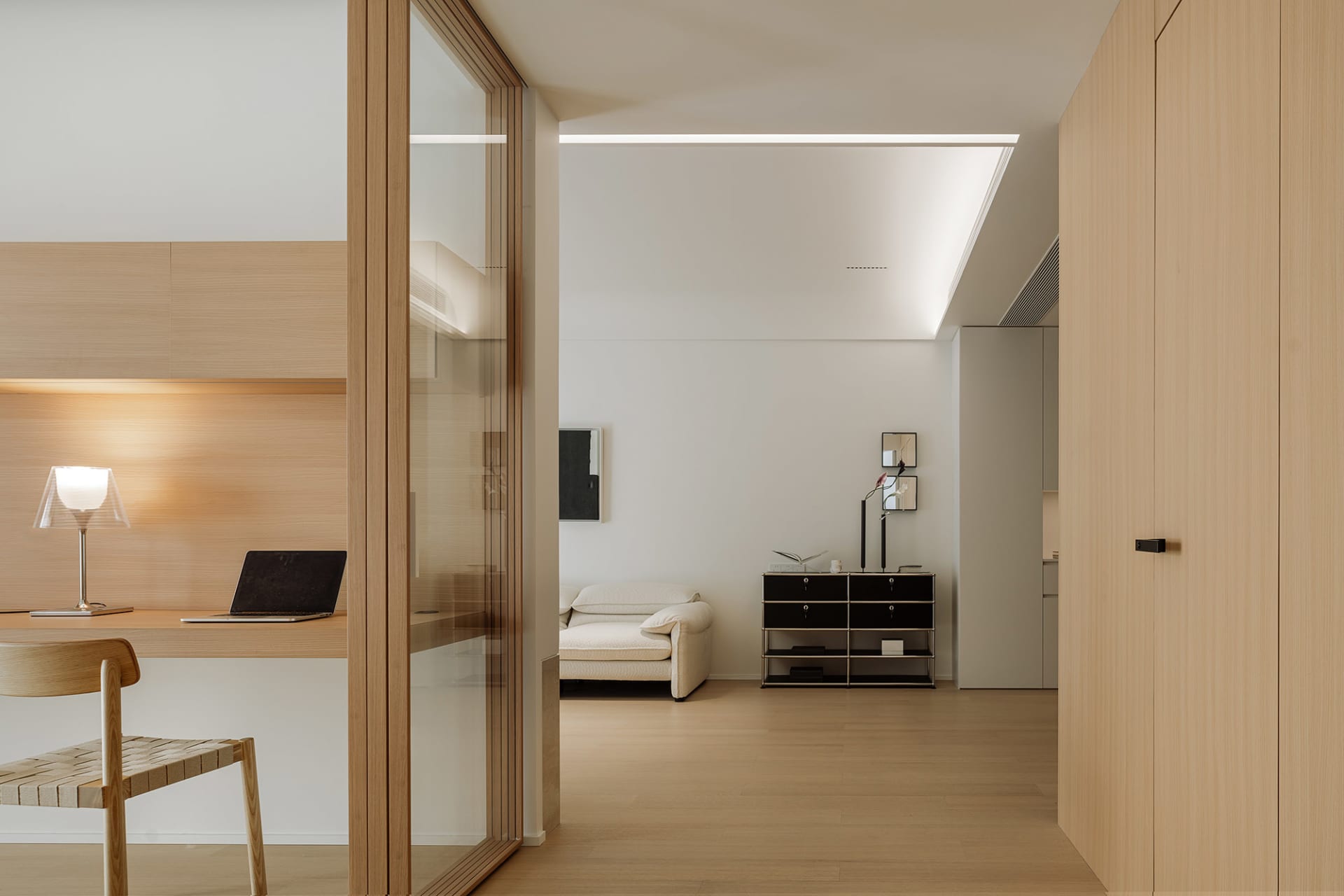 A modern minimalist living room with wooden furniture, white walls, and a couch.