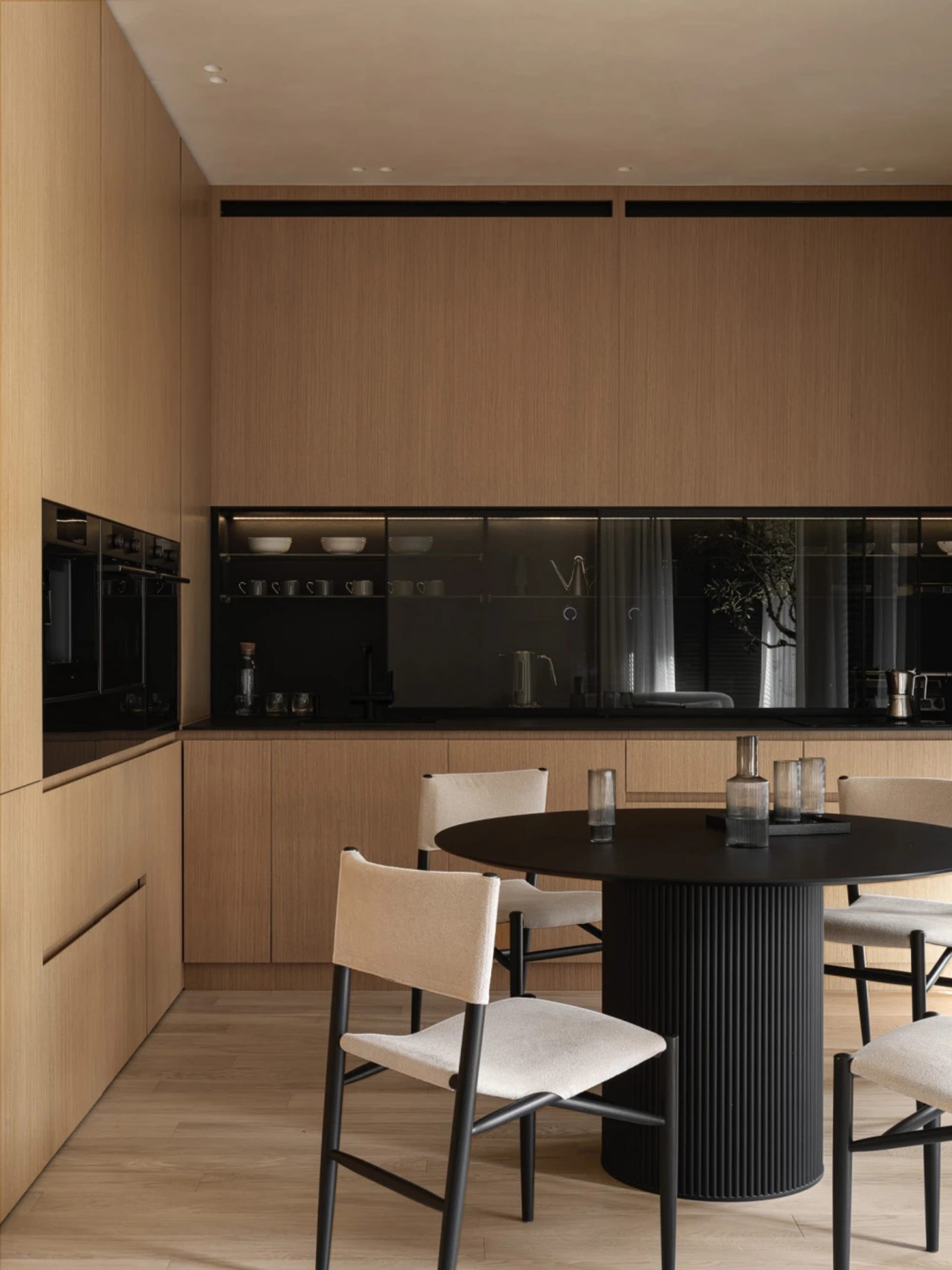 Modern kitchen with minimalist design featuring wooden cabinets and glass elements.