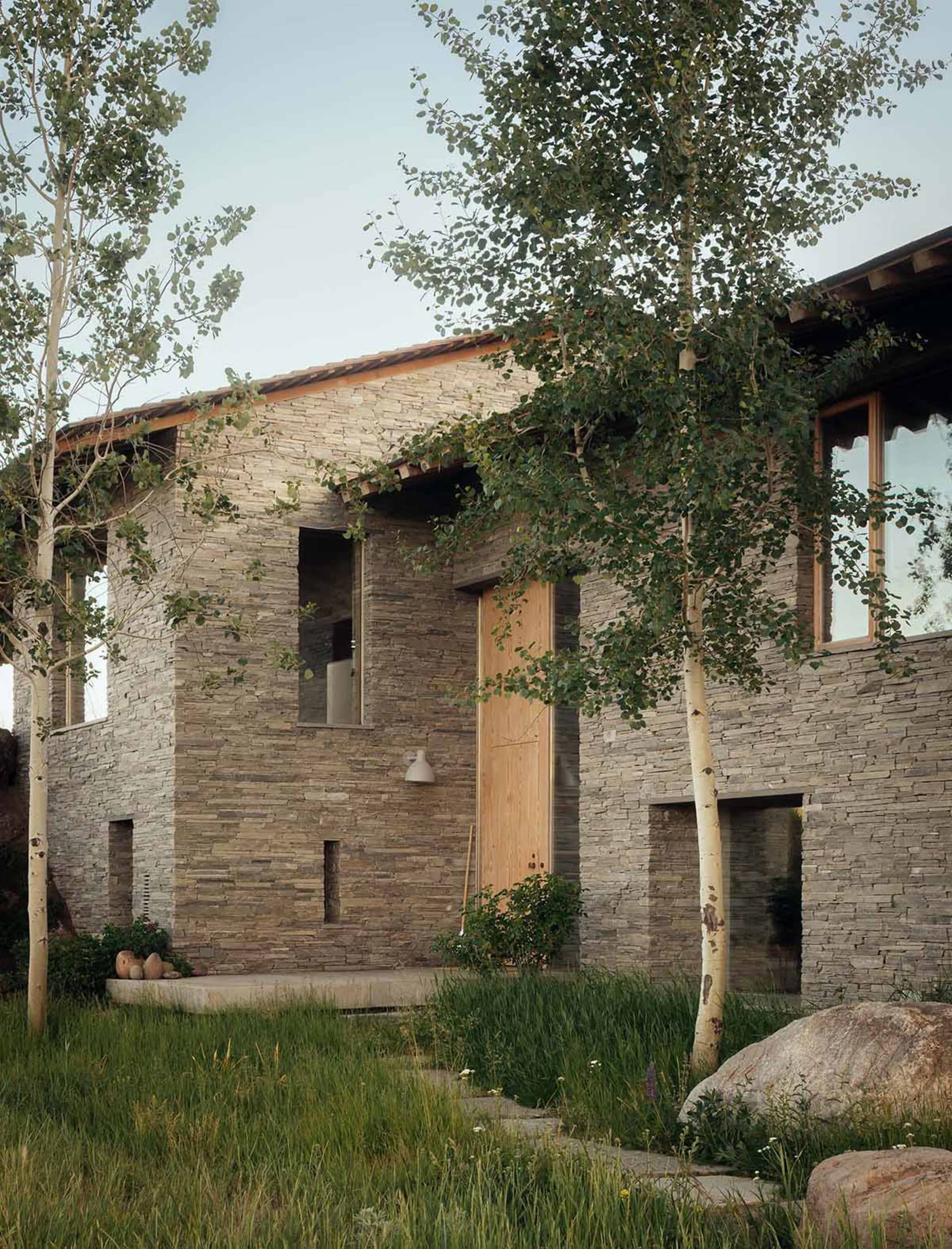 Modern residential building with stone exterior and greenery
