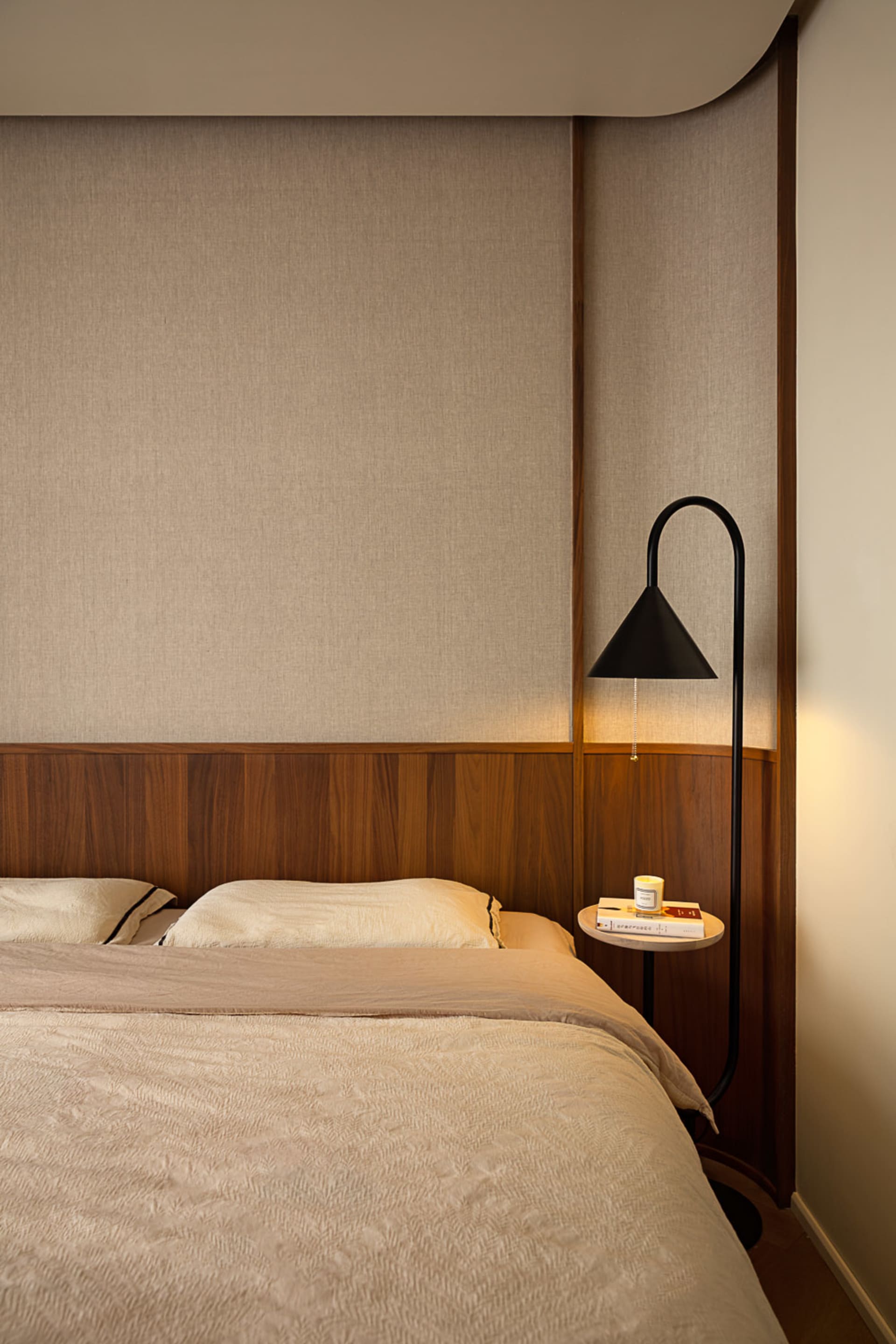 A bedroom with neutral-toned walls and furniture, featuring a bed with soft lighting and minimal decor.