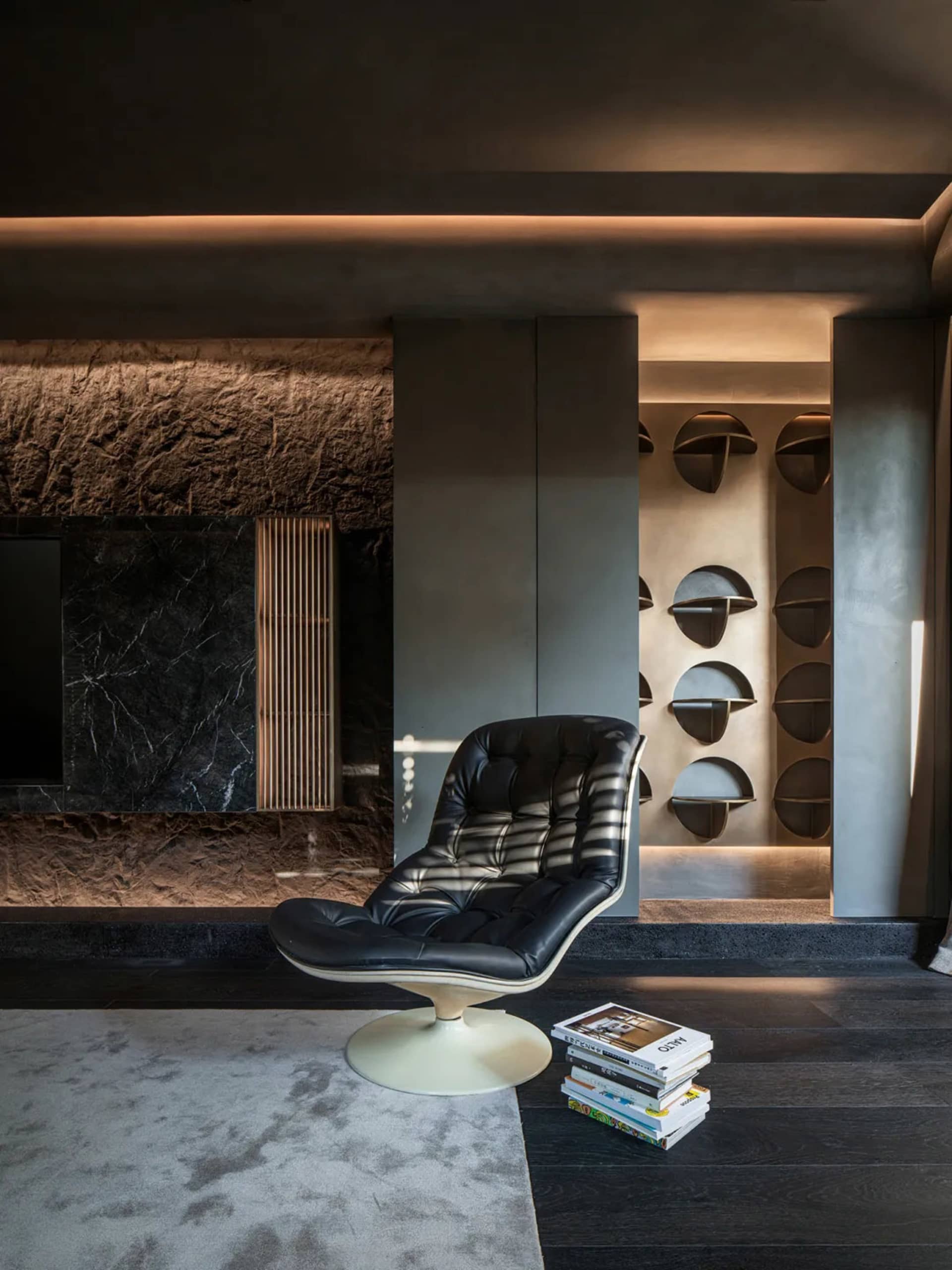 Modern living room featuring a black leather swing chair on a black wooden floor with a gray rug, illuminated by warm lightin