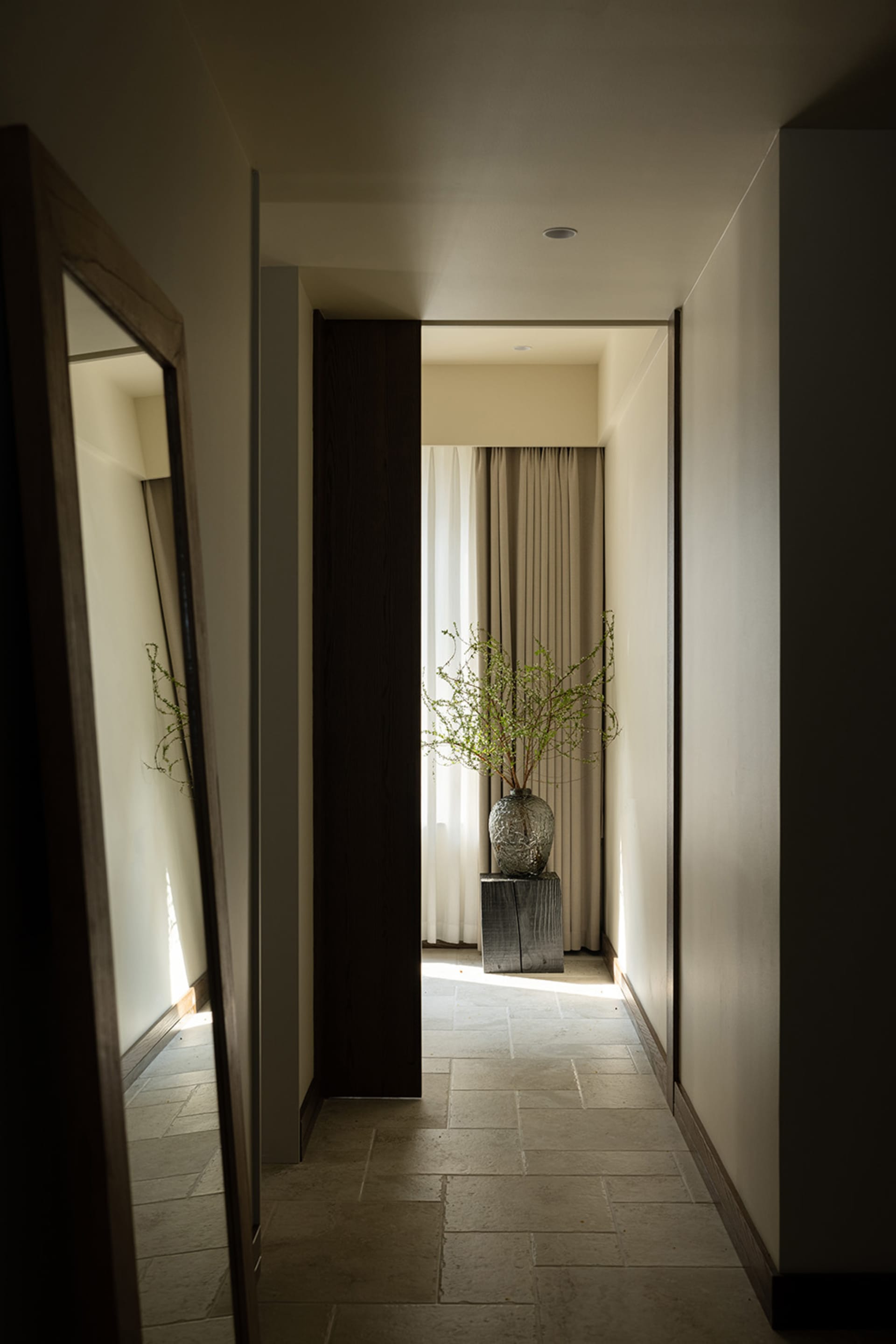 Modern minimalist entryway with white walls, stone flooring, and wooden accents.