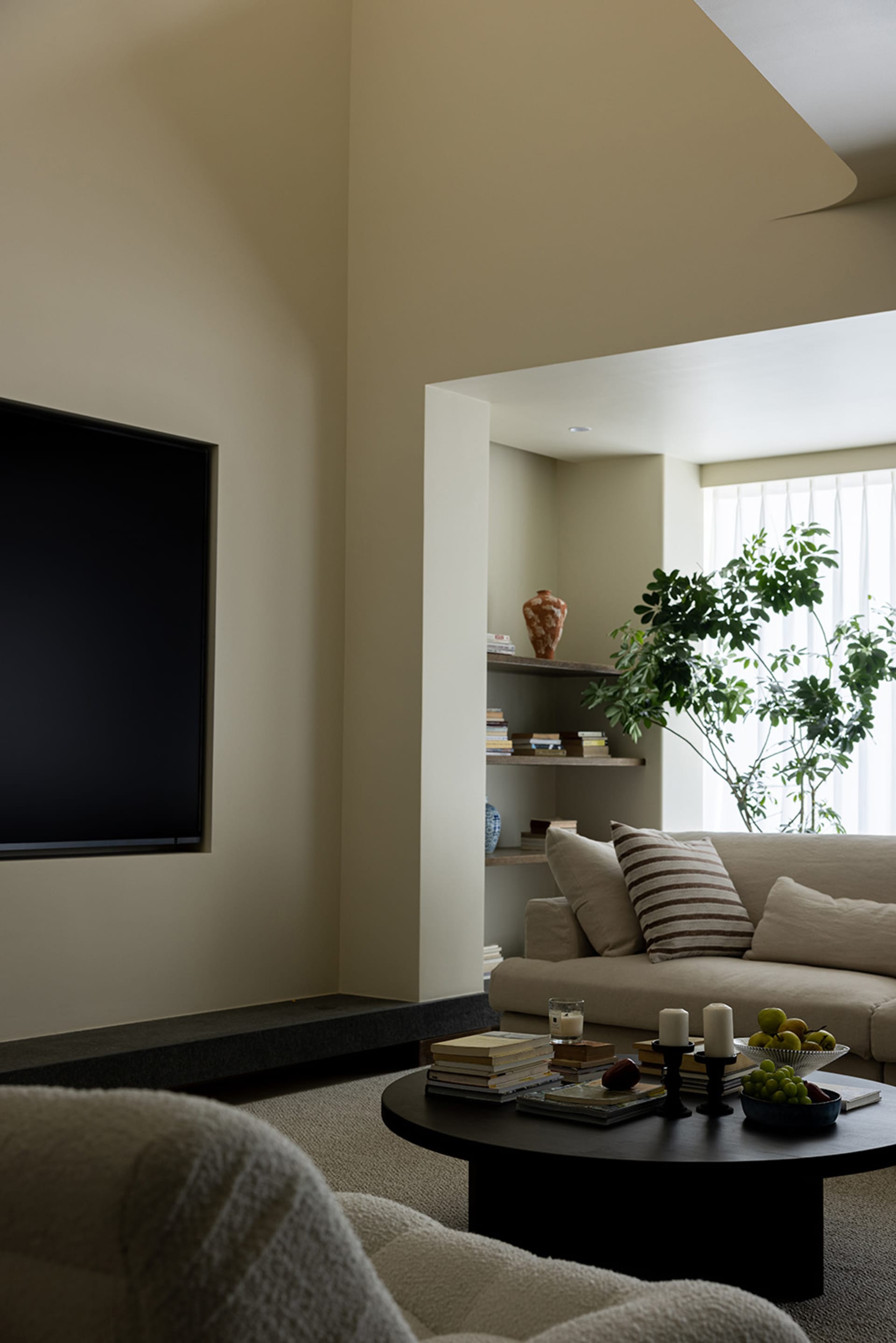 A modern living room with a neutral color palette featuring a couch, coffee table, and bookshelf.