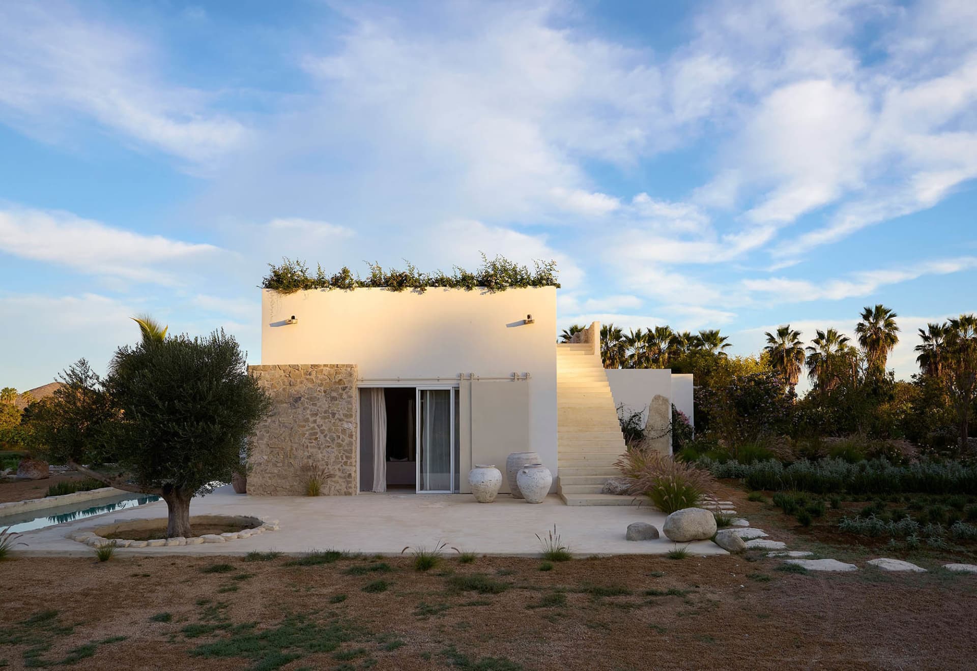 A modern residential exterior featuring white stucco and stone elements.