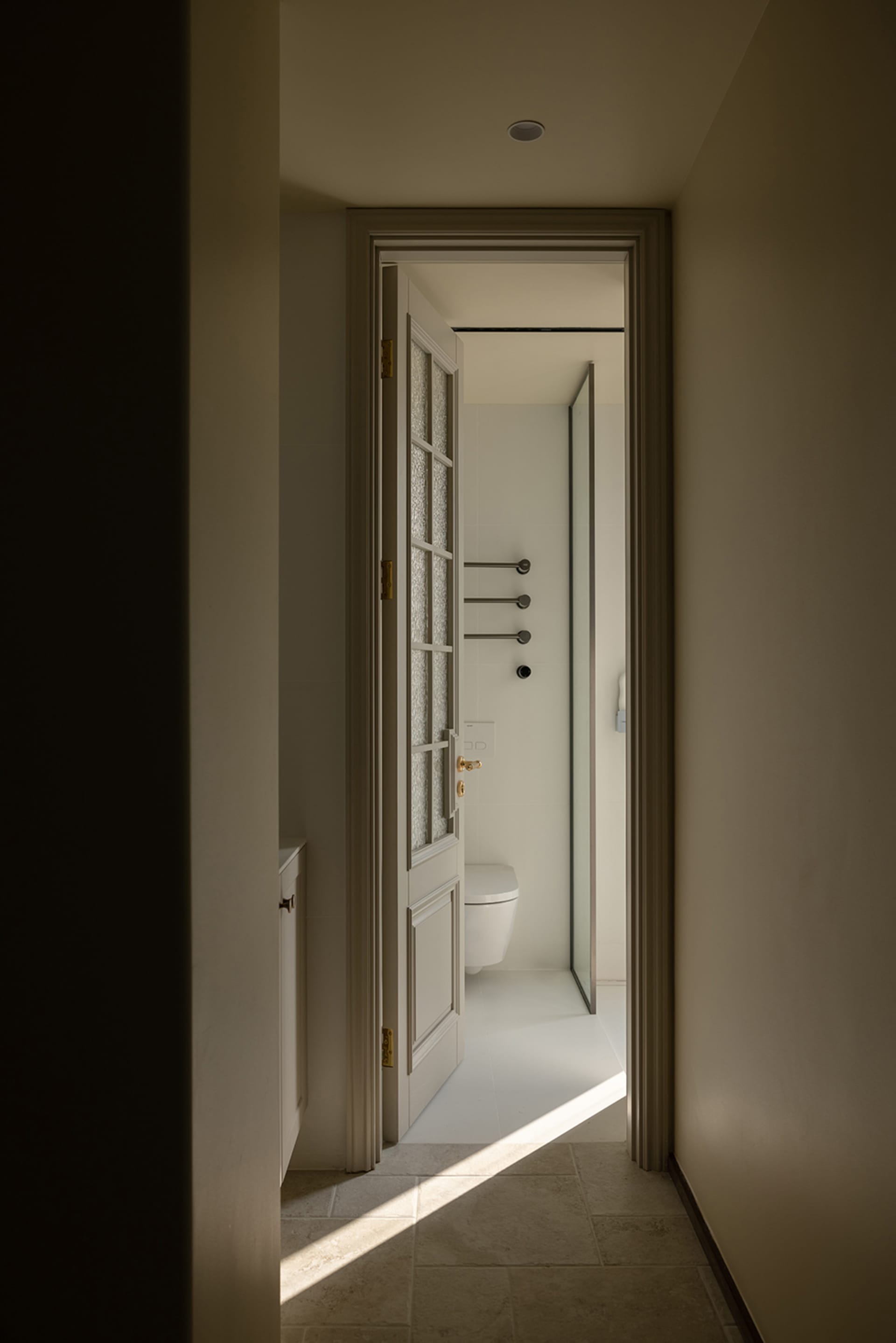 A minimalist bathroom with white tiles and a toilet.