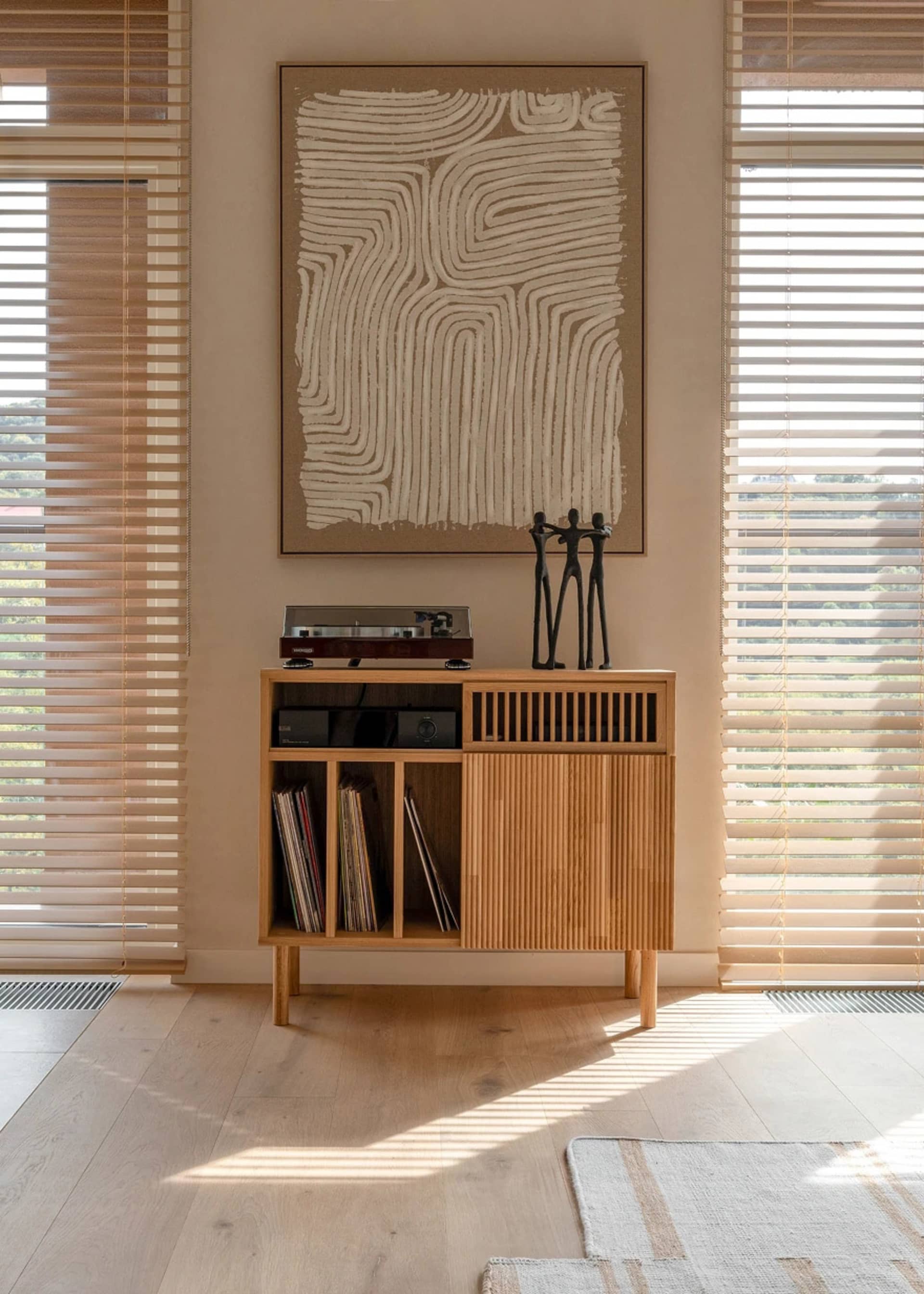 A modern living room featuring a wooden cabinet displaying various items and a large abstract art piece.
