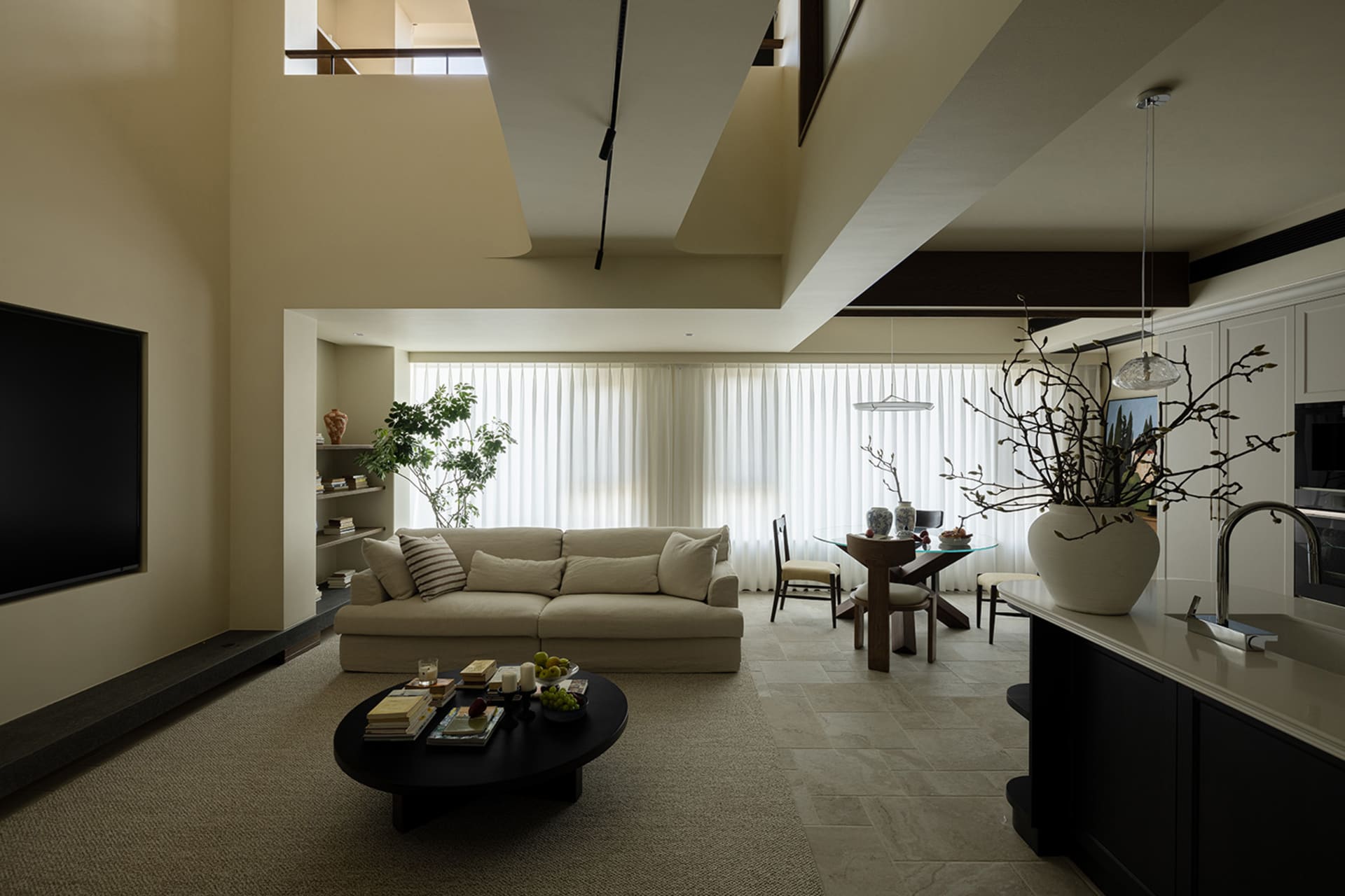A modern minimalist living room with neutral colors and clean lines, featuring a beige sofa, a round coffee table, and a larg