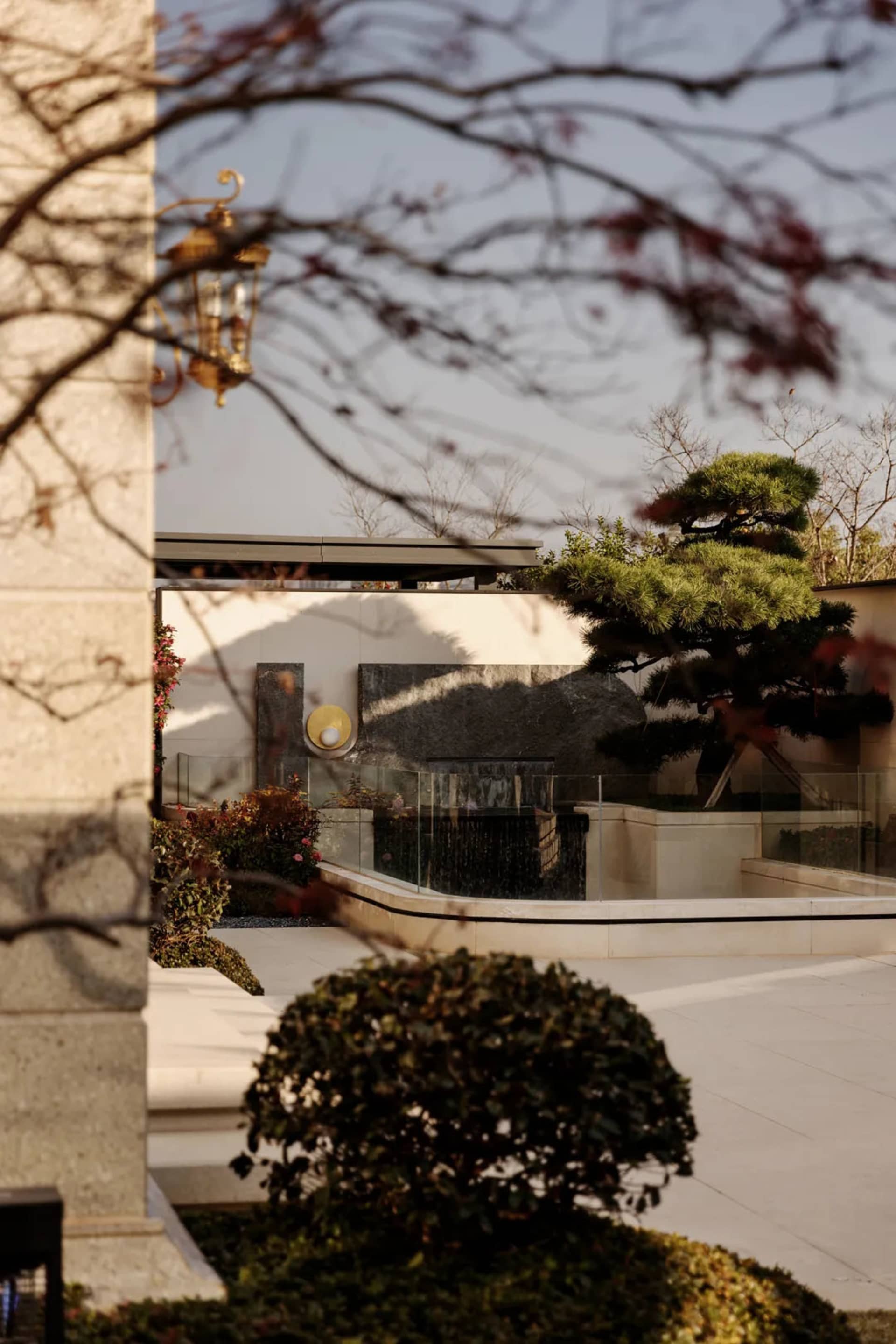 以混凝土元素打造的現代庭院，設有噴泉與景觀植栽。
