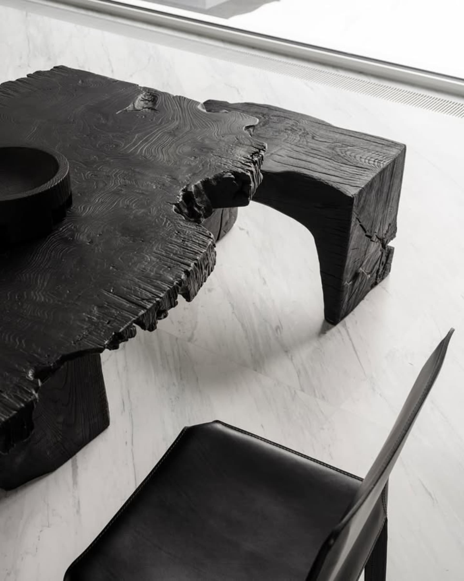 A modern, industrial-style black wooden table with a natural, raw finish.