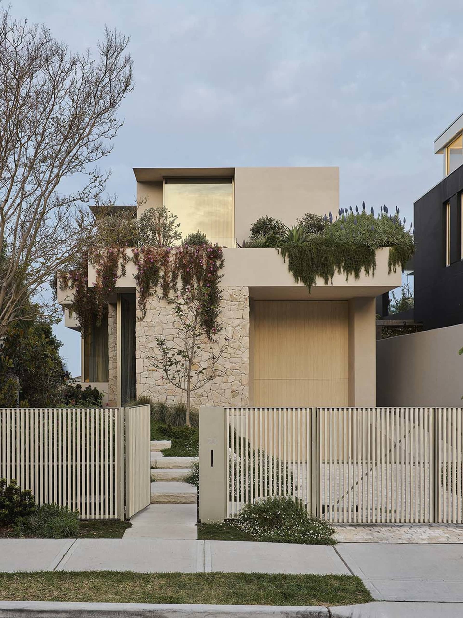 Modern house with concrete and stone exterior adorned with green plants.