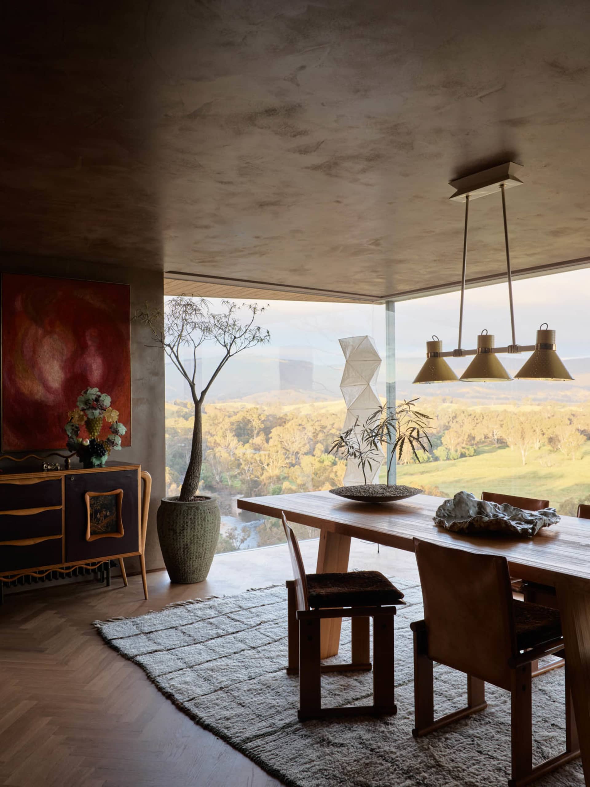 A modern living room featuring wooden furniture and decor, with a panoramic view of the landscape.