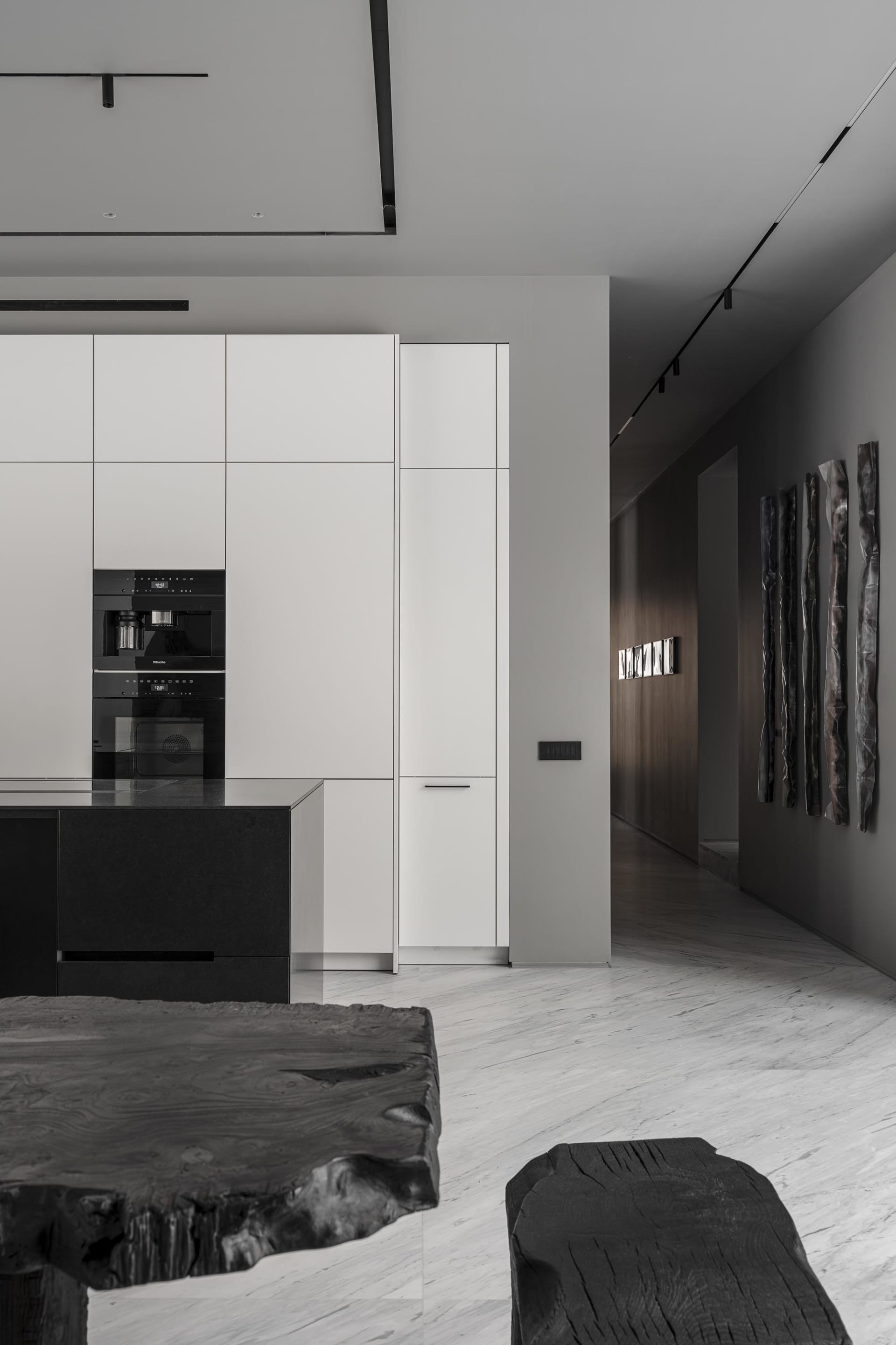 Modern white kitchen interior featuring minimalist black marble countertops and cabinets.