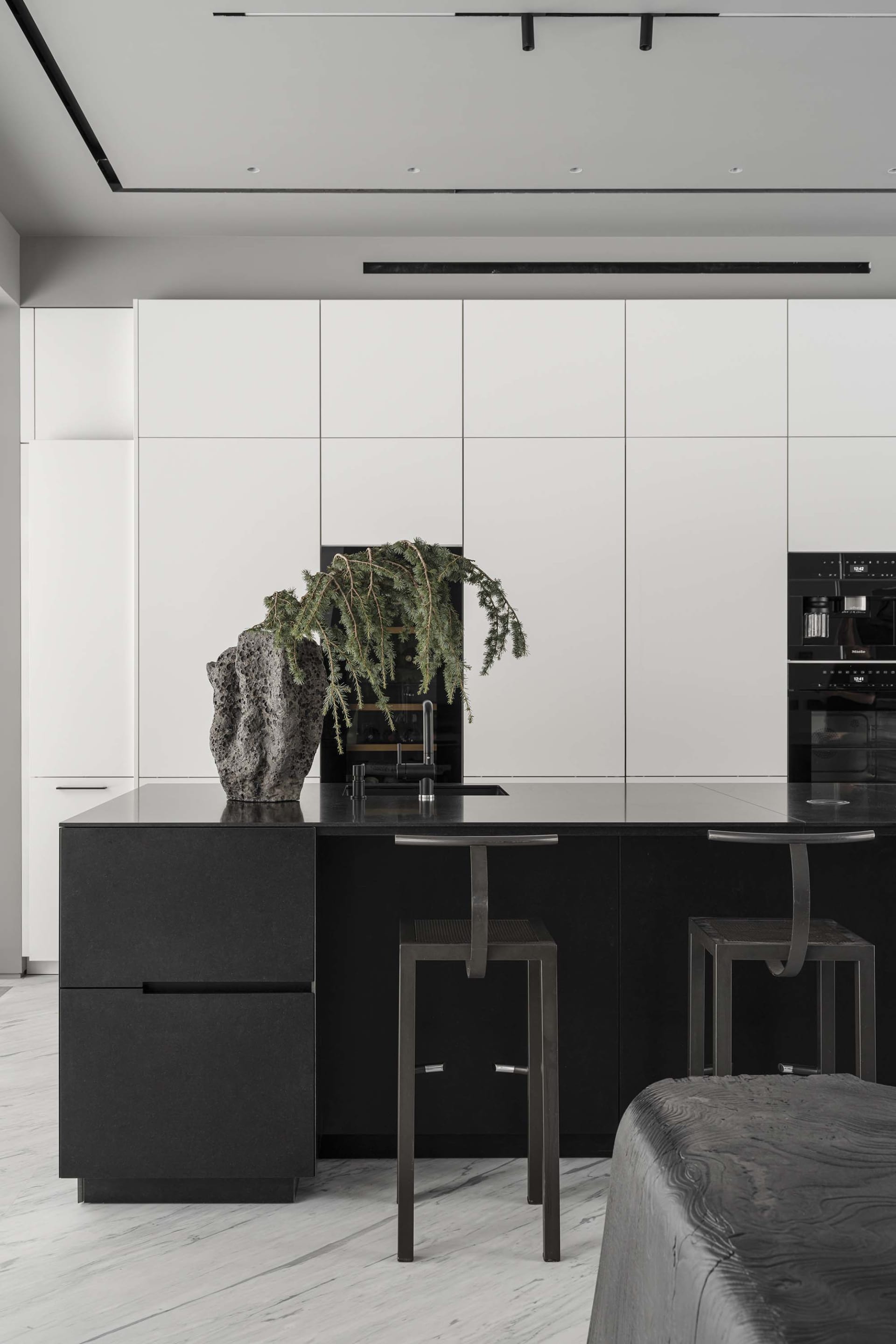 Modern kitchen with black and white interior, featuring a minimalist island with black countertops, white walls, and modern a