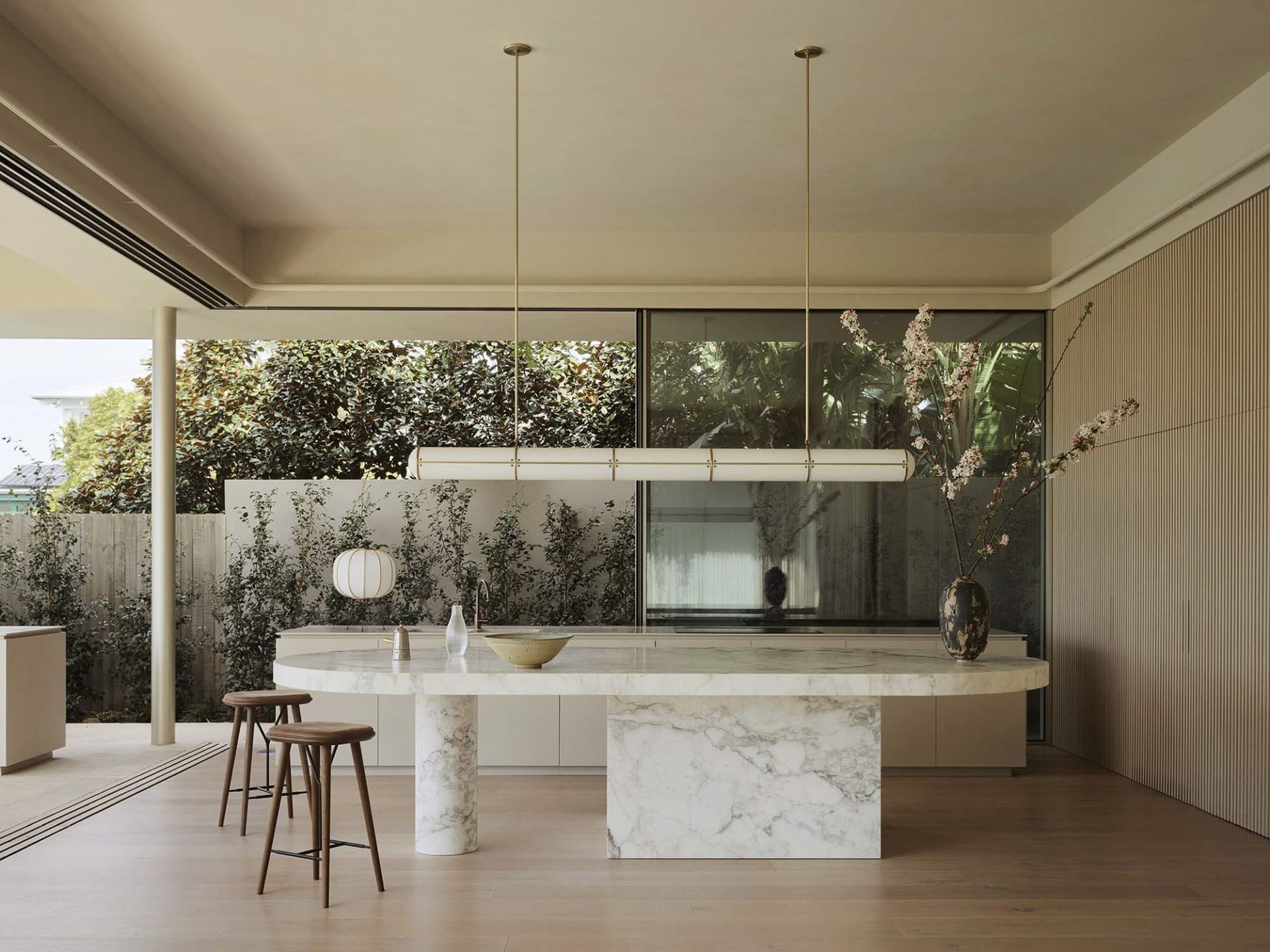 Modern kitchen interior featuring a marble countertop and island, with a minimalist aesthetic and large windows.
