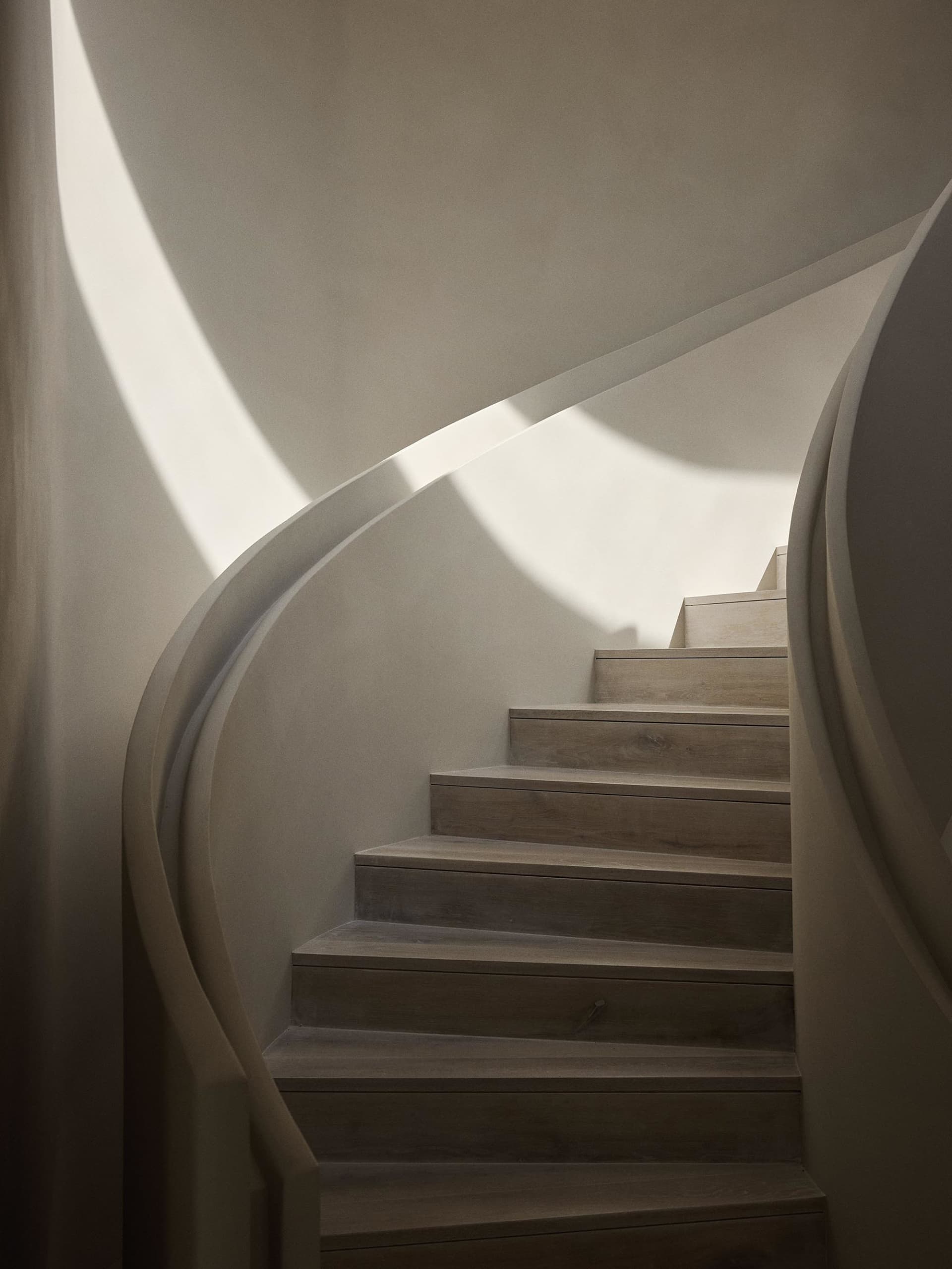 A minimalist staircase made of wood, featuring smooth, curved lines.