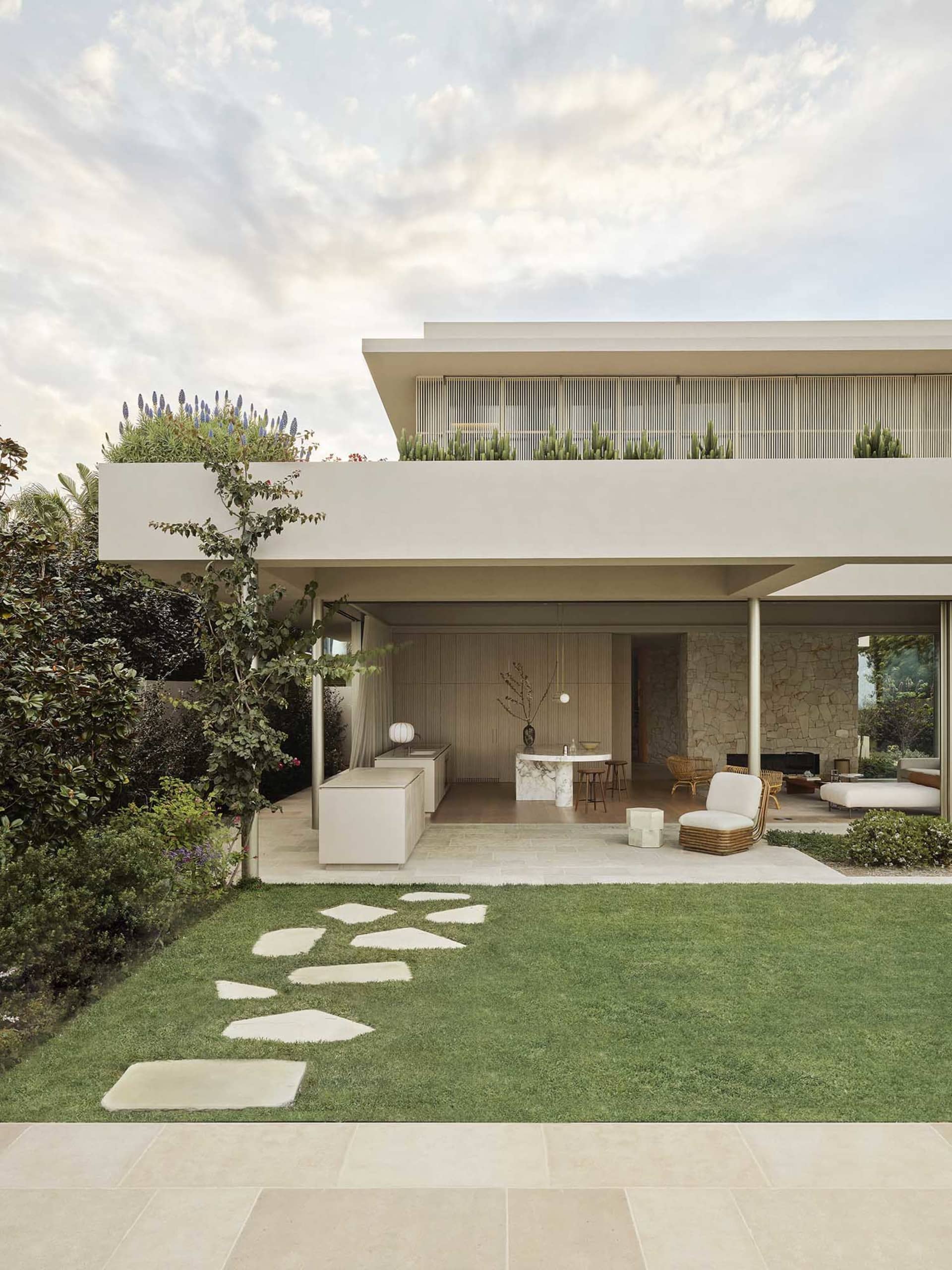 Modern residential home exterior with sandstone facade and rooftop garden.
