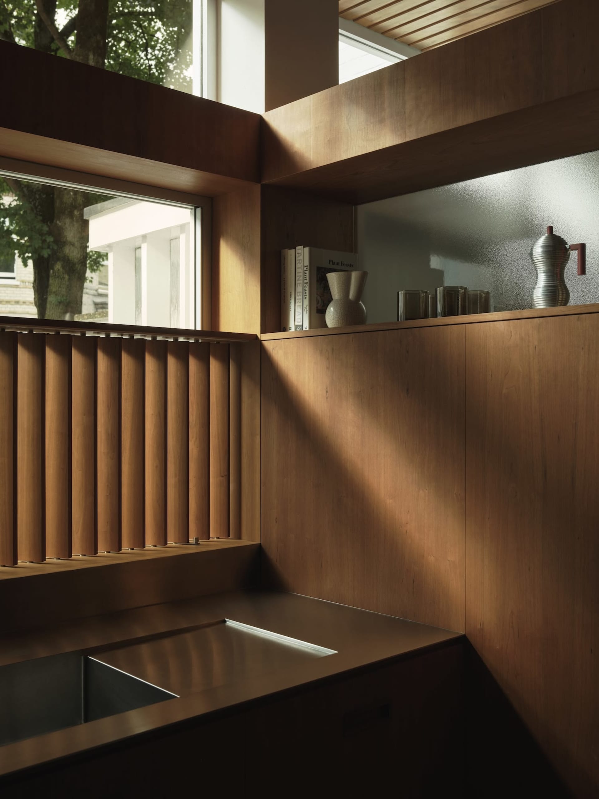 A minimalist kitchen featuring wooden shelves and a stainless steel sink.
