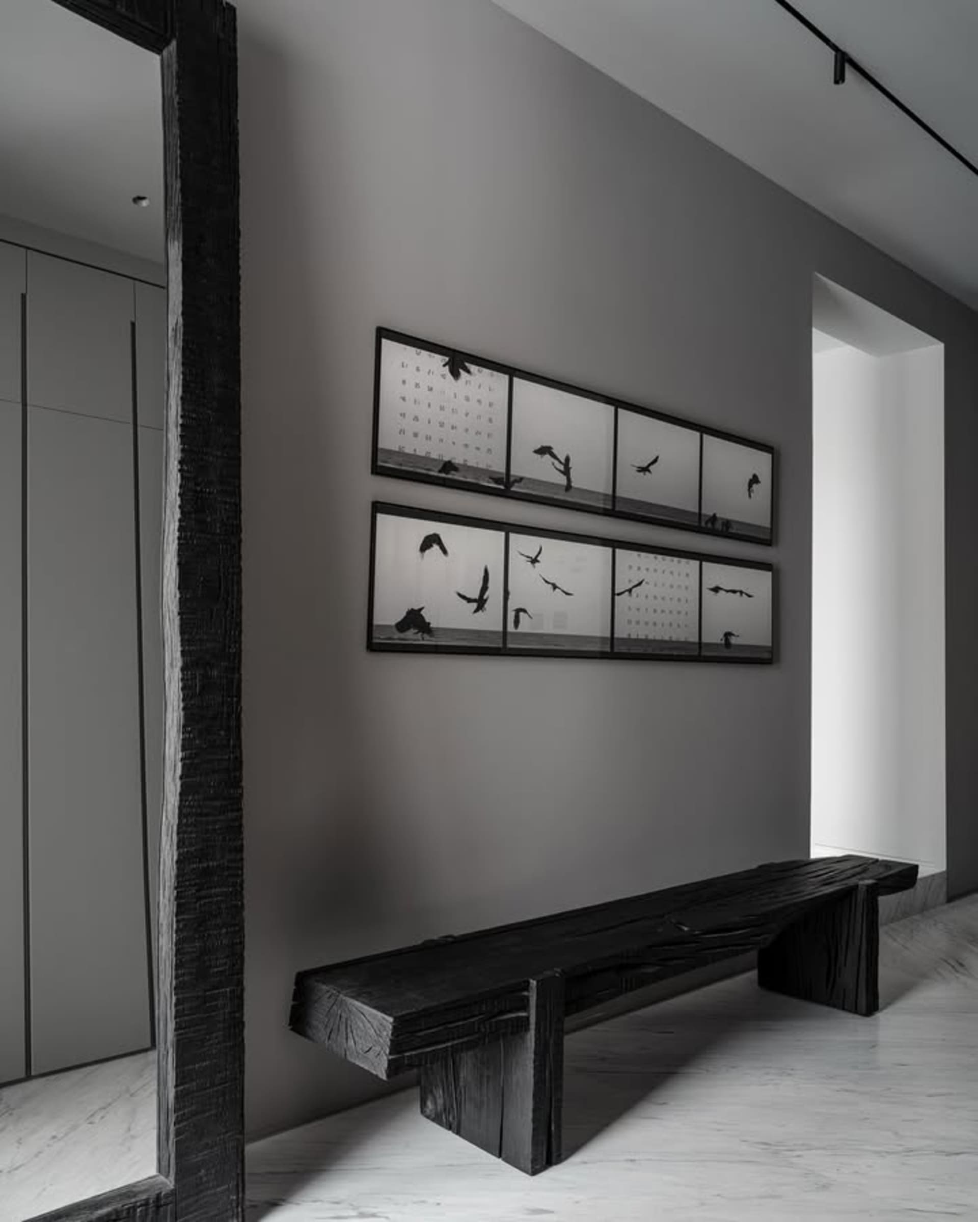 Industrial-style interior design featuring a wooden bench with black and white photography of birds on the wall.
