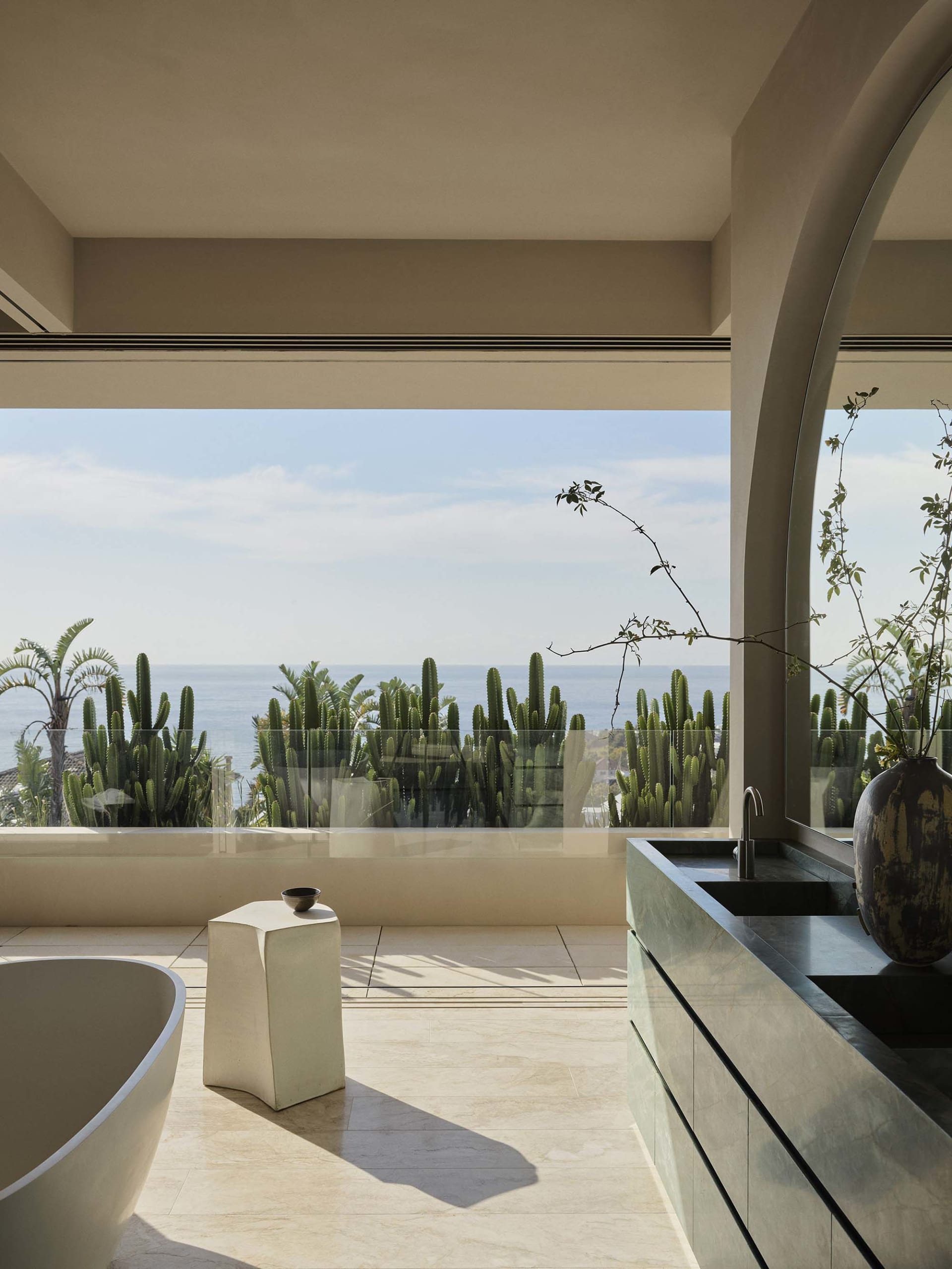 Modern minimalist bathroom featuring marble countertops, concrete walls, and ceramic tiling with a view of the ocean.